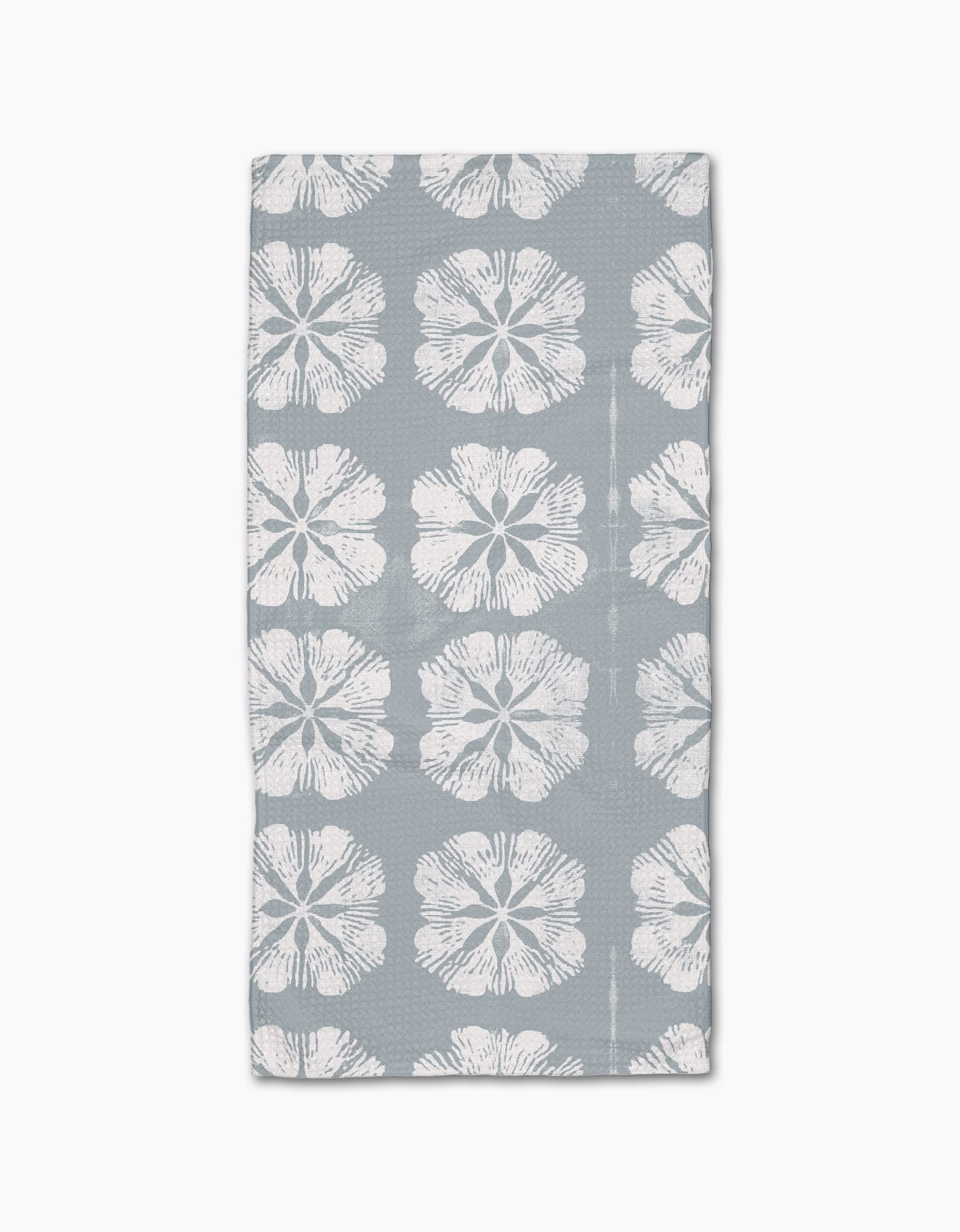 The Gracie Bar Towel by Geometry is rectangular, gray, and made with Geoweave fabric, featuring rows of large white hibiscus flowers on a plain background.