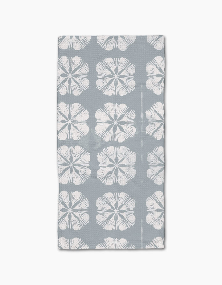 The Gracie Bar Towel by Geometry is rectangular, gray, and made with Geoweave fabric, featuring rows of large white hibiscus flowers on a plain background.