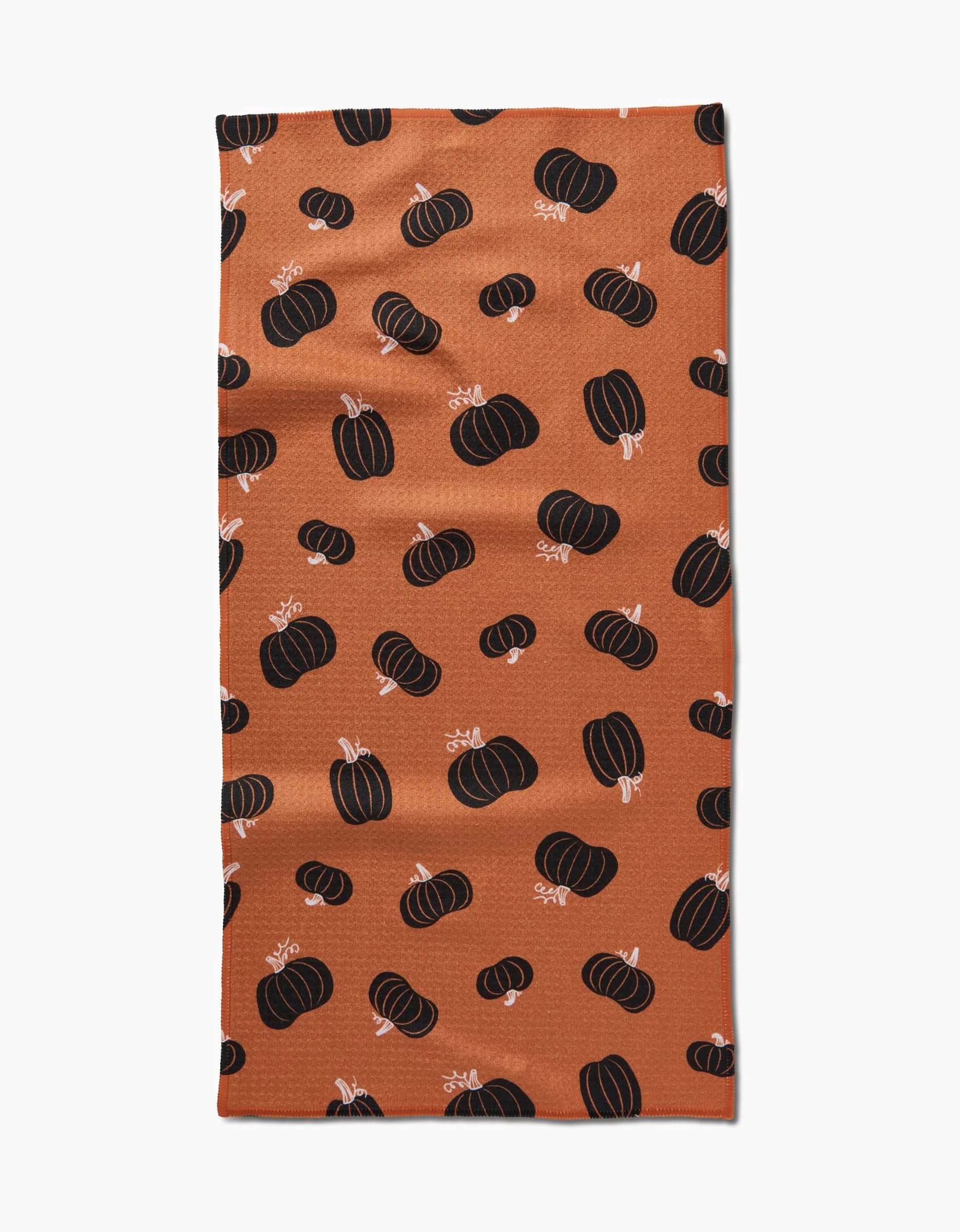 The Halloween Black Pumpkins bar towel by Hufton Studio is a rectangular orange towel made from recycled materials, featuring a design of black pumpkins with white stems scattered across the surface.