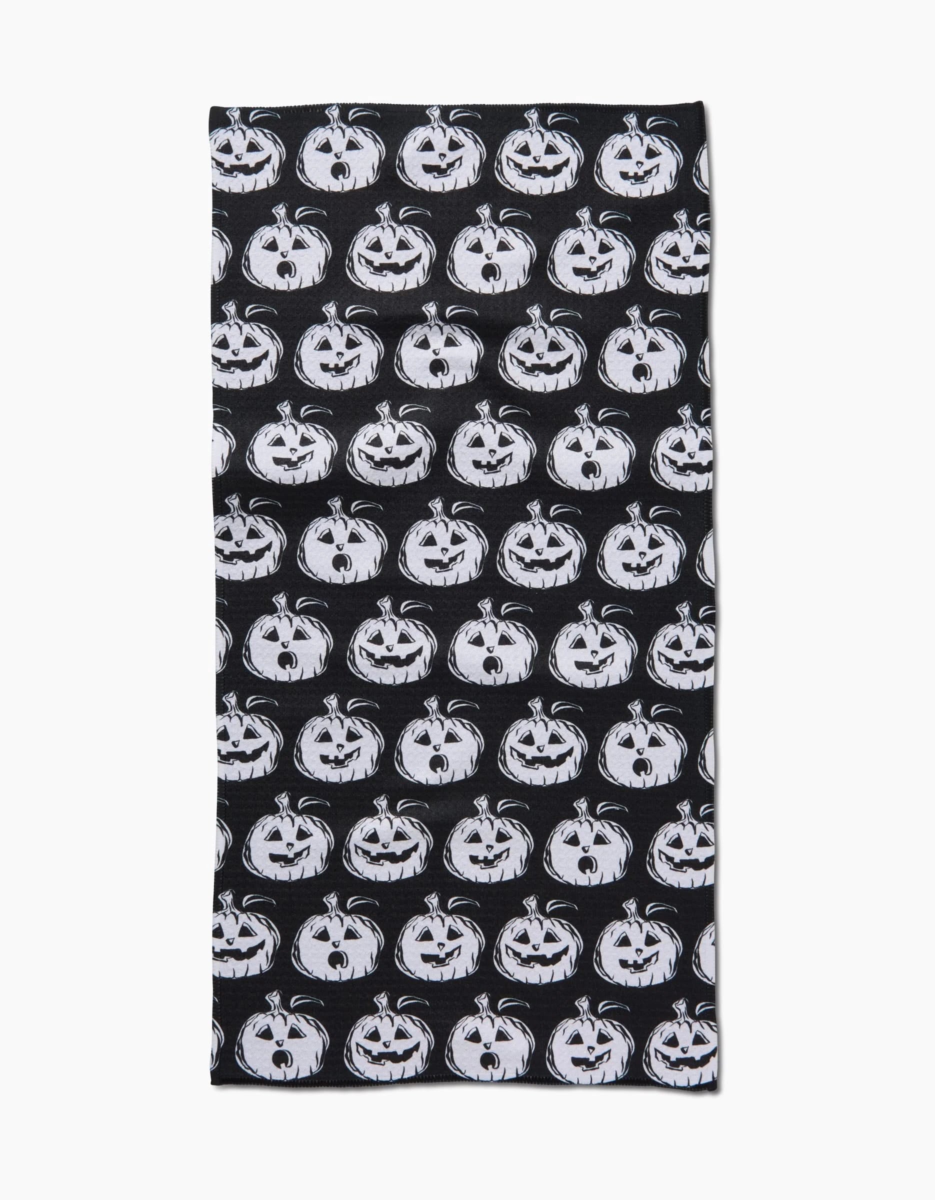 The Halloween Pumpkins bar towel by Aubrey Fairchild features a black rectangle design with a repeating pattern of white, cartoon-style jack-o-lantern faces and is ultra-absorbent—ideal for festive clean-ups.
