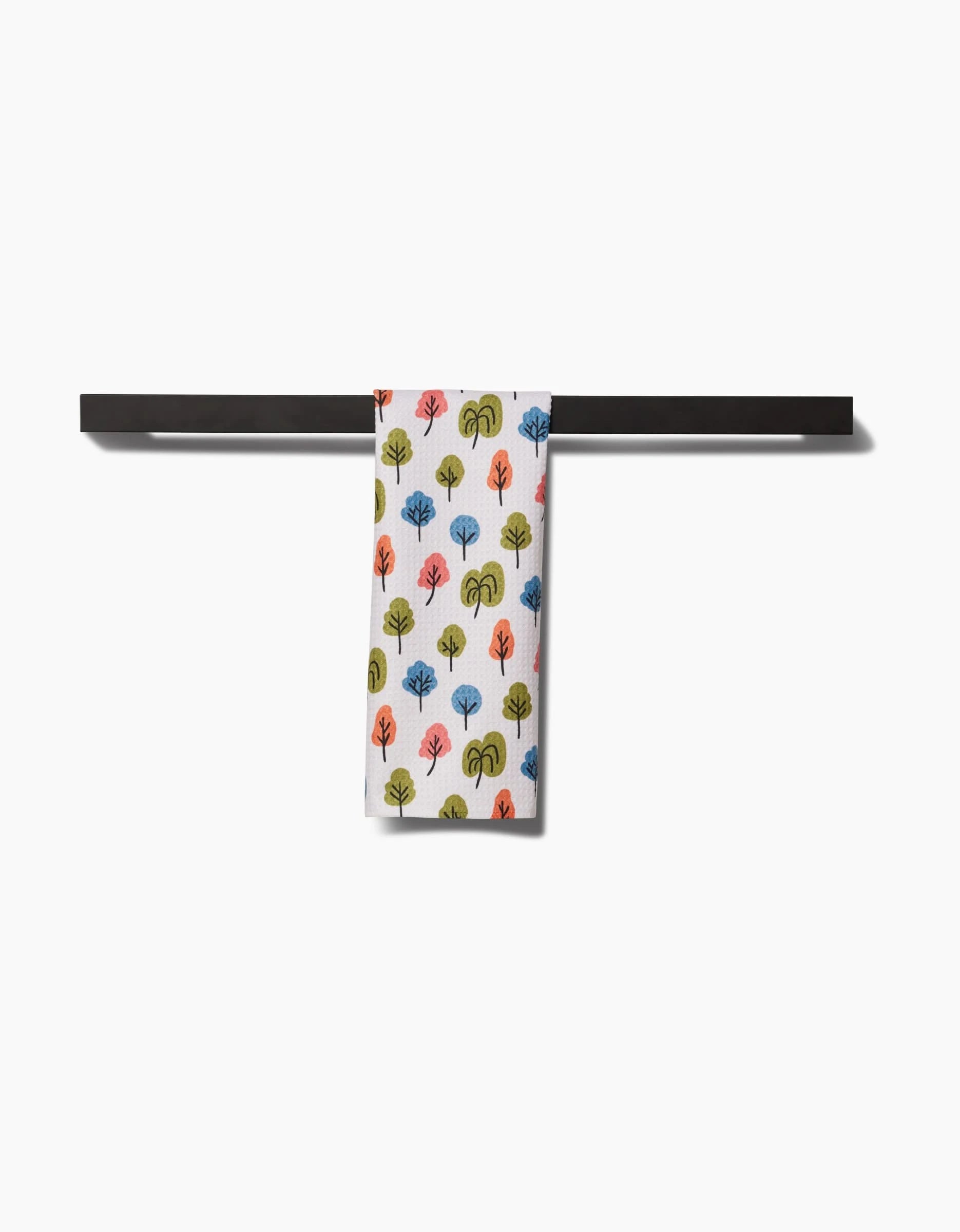 The Kayla Ann Happy Trees Bar Towel, crafted from Geoweave fabric, features a colorful repeating tree pattern and hangs neatly on a black rack against a white background, blending style and function.