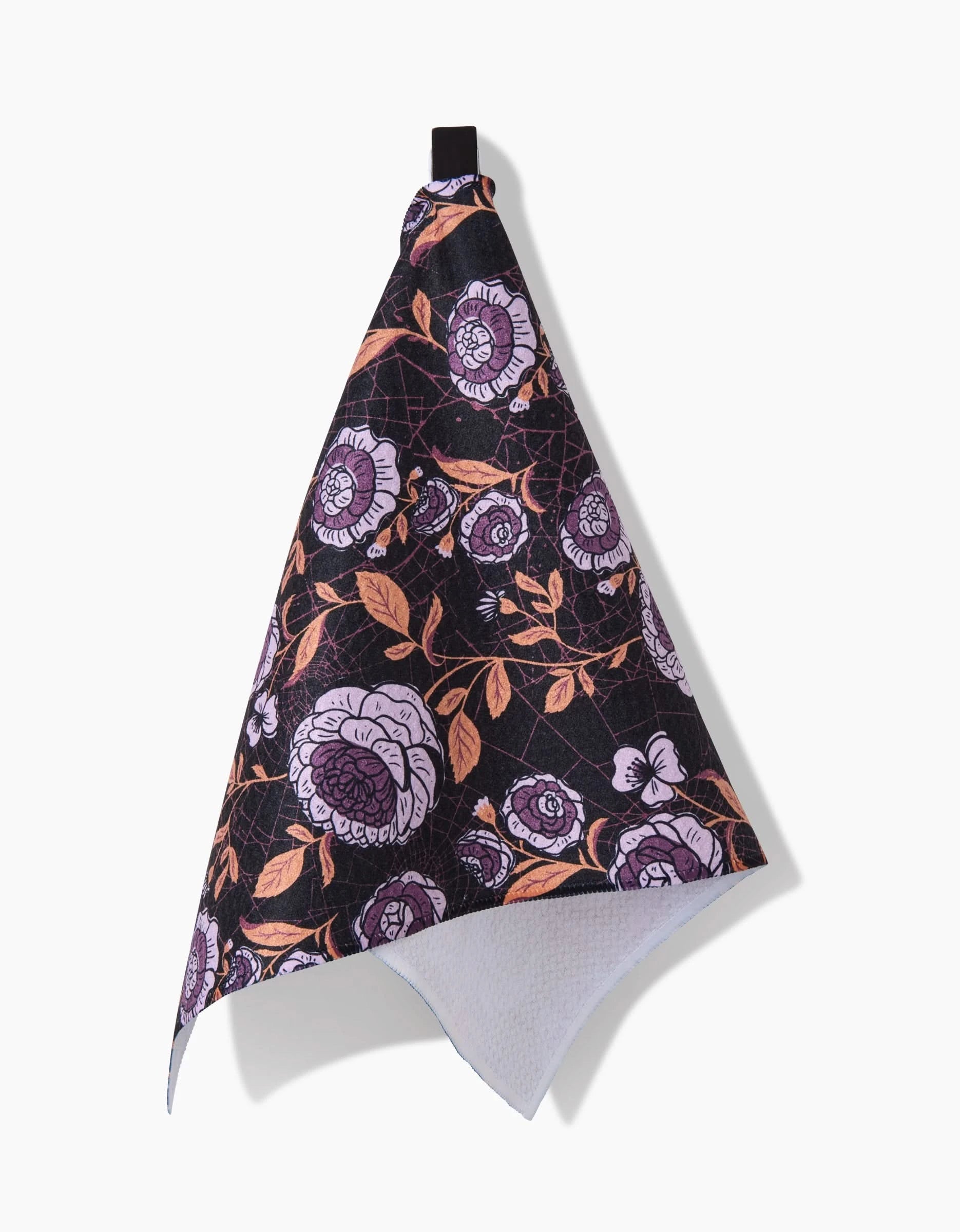 The Haunted Roses towel by Danelys Sidron is a black, ultra-absorbent towel with a hanging loop, decorated with pink, white, and orange floral patterns, shown against a white background.