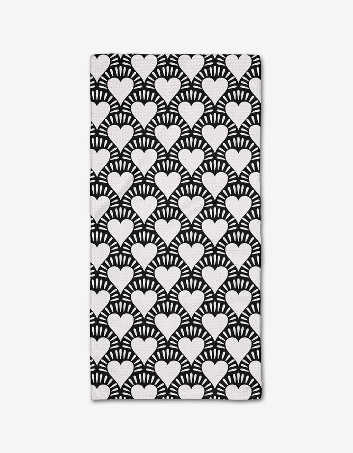 The Heartthrob Onyx bar towel by Charlie Rowan Designs is made from Geoweave fabric and showcases bold, high-contrast white hearts with radiating lines on a black background for a striking geometric look.