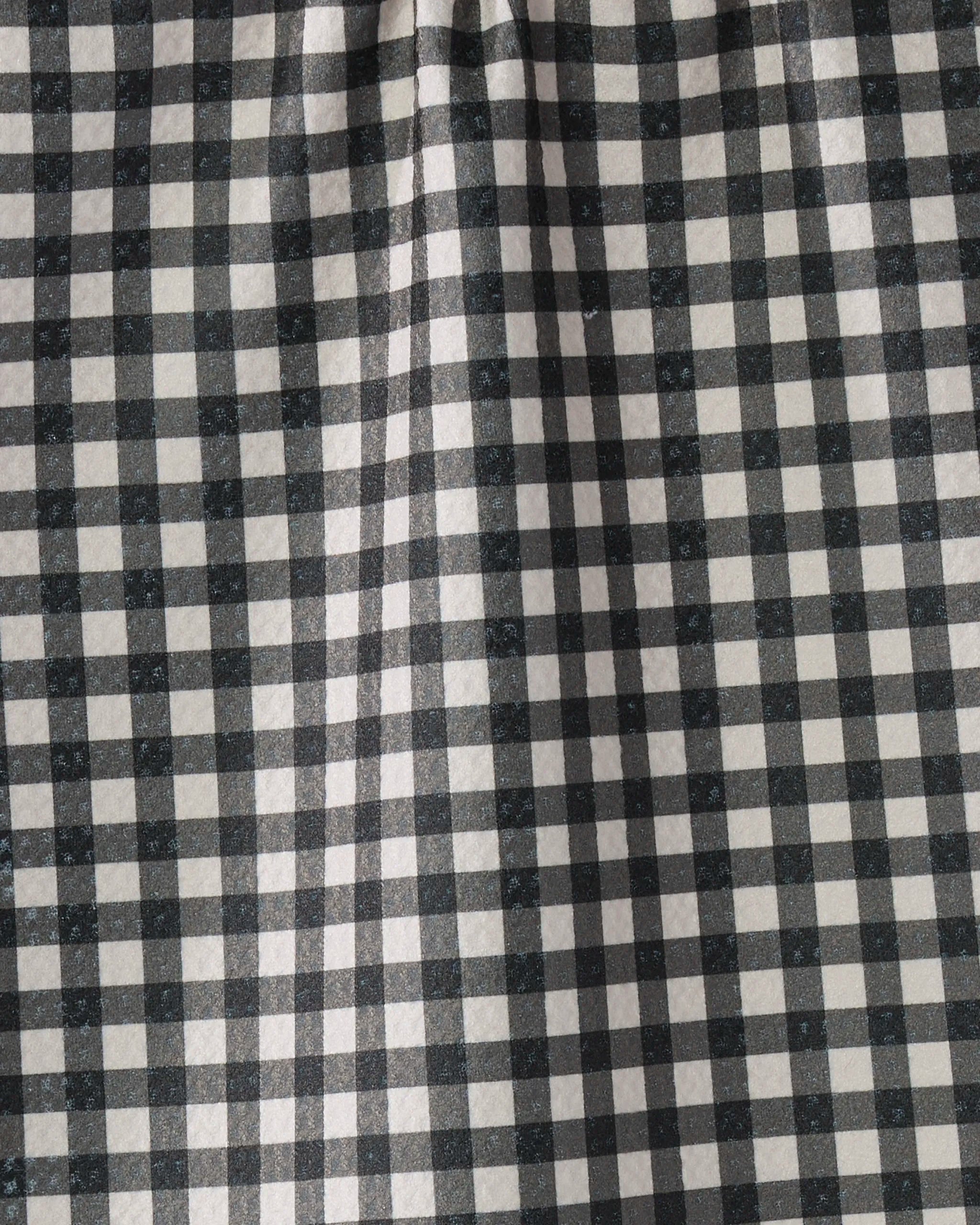 The Geometry Heritage kitchen towel features a black and white gingham checkered pattern with small, evenly spaced squares and slight gathers at the top for gentle folds.