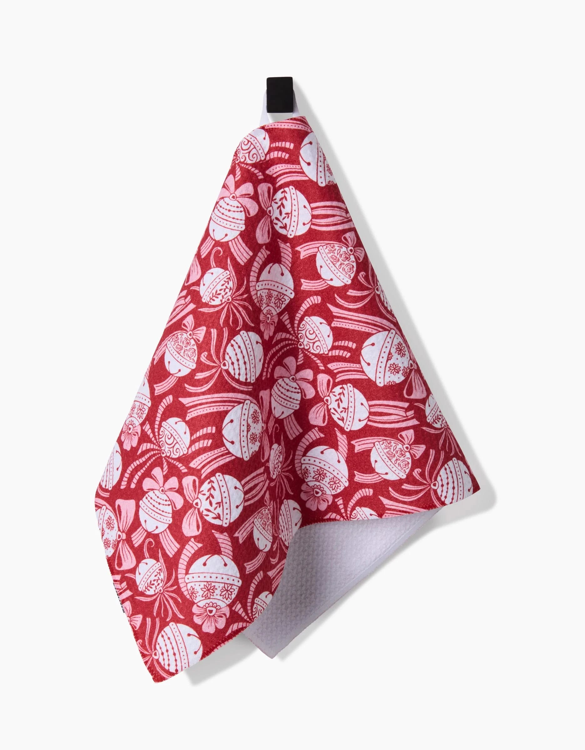 The Holiday Bells Bows bar towel by Sarah Daugherty features festive red and white Christmas ornaments and holly leaves, is crafted from recycled materials, and hangs from a black loop against a white background.