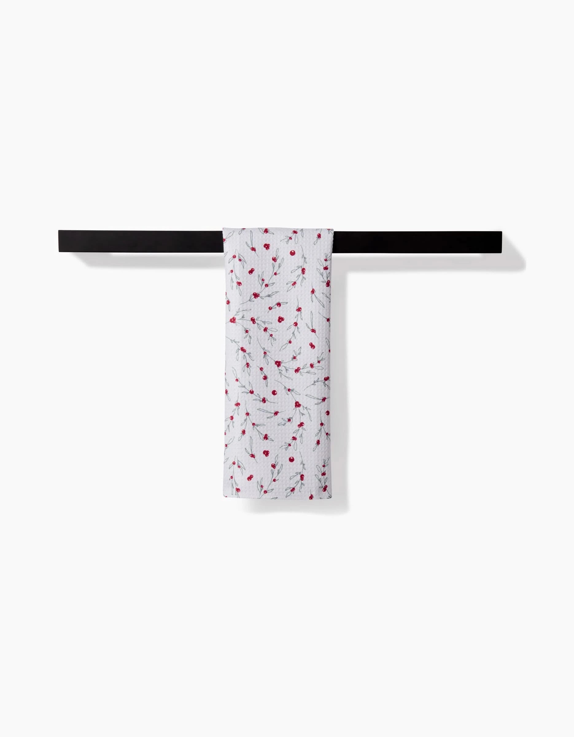 The Ashley Celena Holiday Sprigs white bar towel, featuring a textured pattern and subtle red accents, made from ultra-absorbent recycled materials, hangs neatly over a black bar against a plain white background.