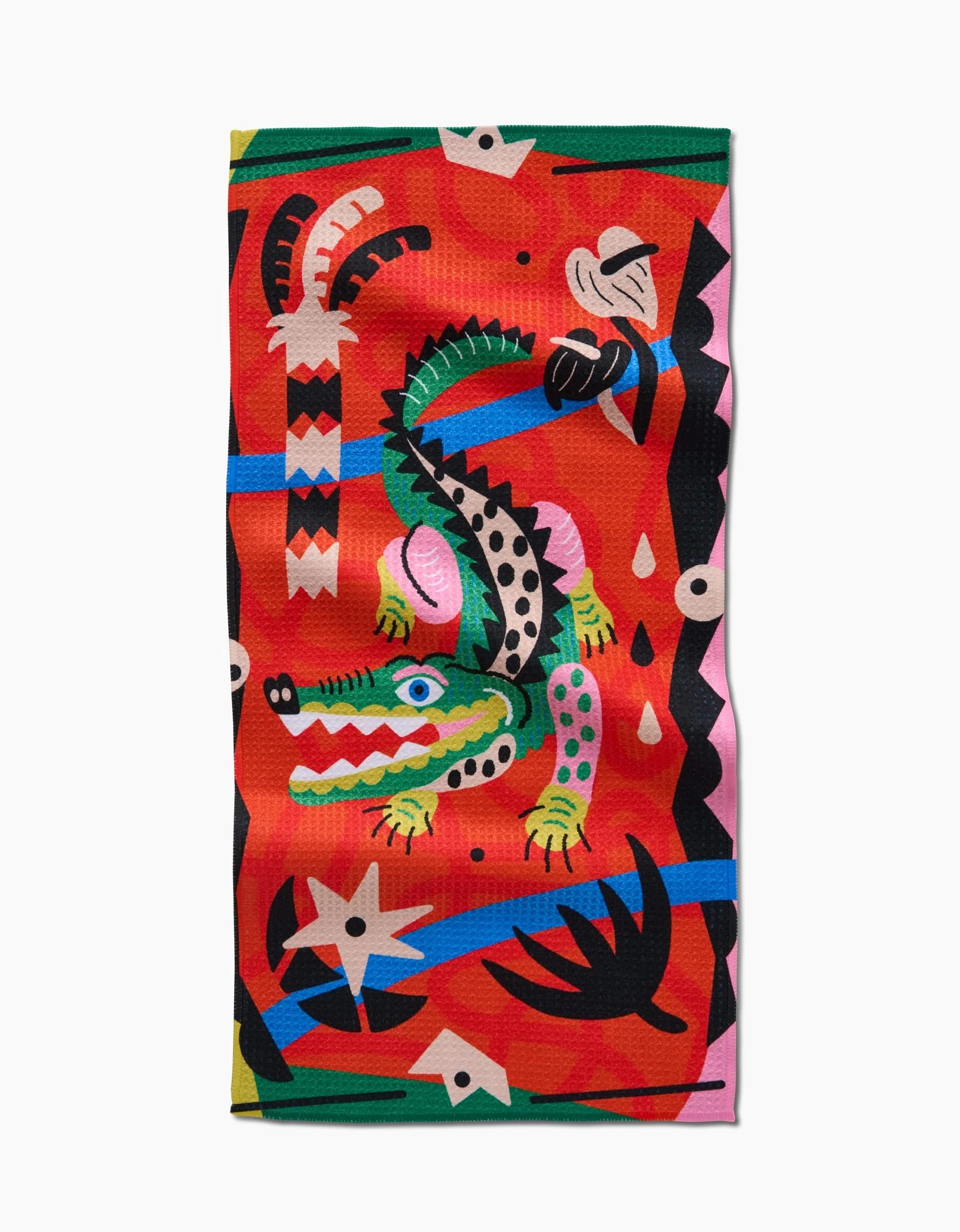 The Jacaré Bar Towel by Camila Leão features a whimsical, multicolored crocodile with geometric patterns and plants on vibrant red Geoweave fabric.