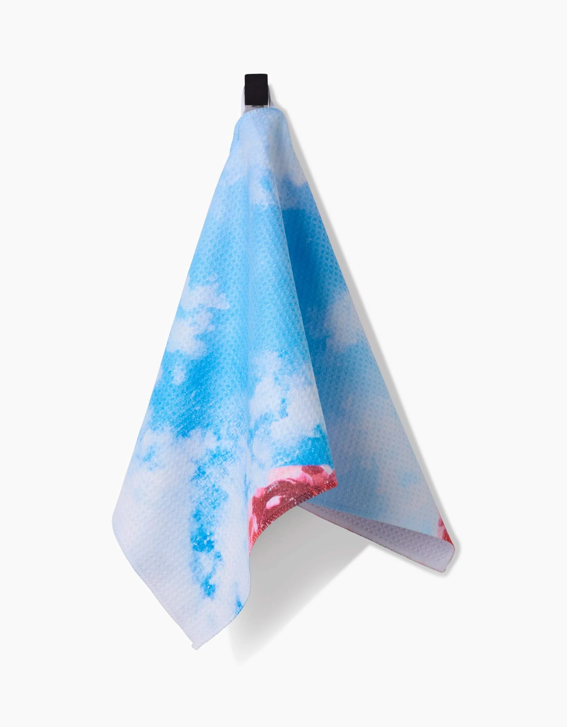 The La Floraison Bar Towel by Stefanie Bales, featuring a blue and white cloud-like pattern with a small red accent, is crafted from ultra-absorbent Geoweave fabric and hangs from a black loop against a white background.
