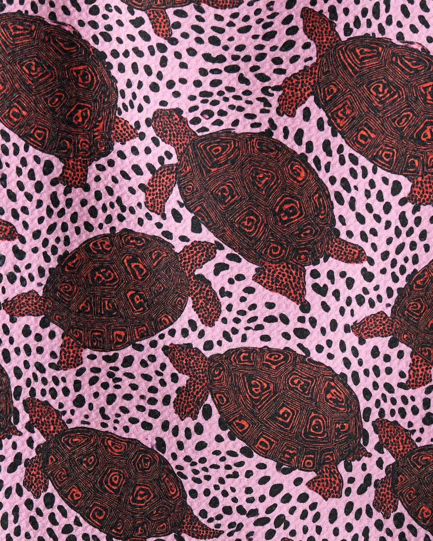 Geometry’s Lagoon Crawl features a geoweave fabric with black and red turtles, each with detailed shells, set against a pink backdrop accented with scattered black dots.