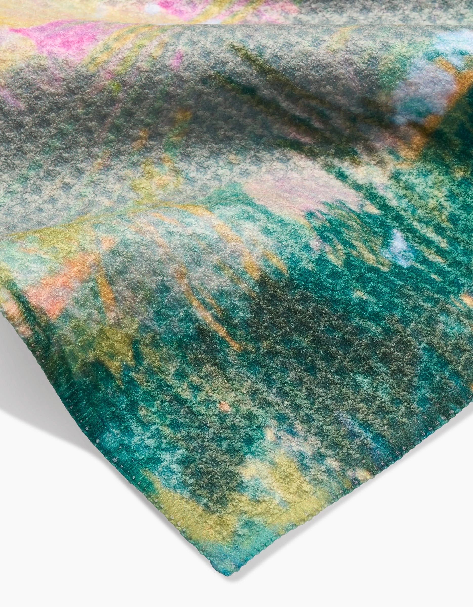 A close-up of the Land of Milk and Honey fabric by Taryn Brennan shows a colorful abstract pattern in green, yellow, pink, and blue on soft Geoweave material with a fuzzy texture and stitched edge.