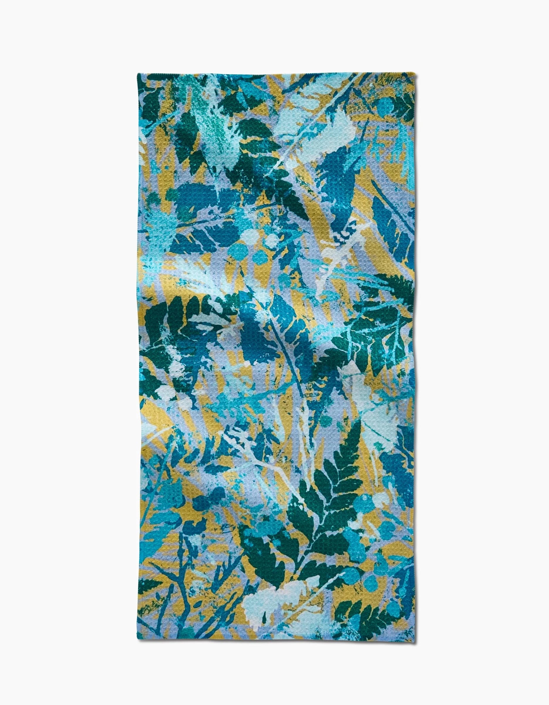 The Leafy Bush bar towel by Taryn Brennan features a vibrant blue, teal, yellow, and white leafy Geoweave pattern with overlapping foliage and abstract brushstrokes for a lively tropical look.