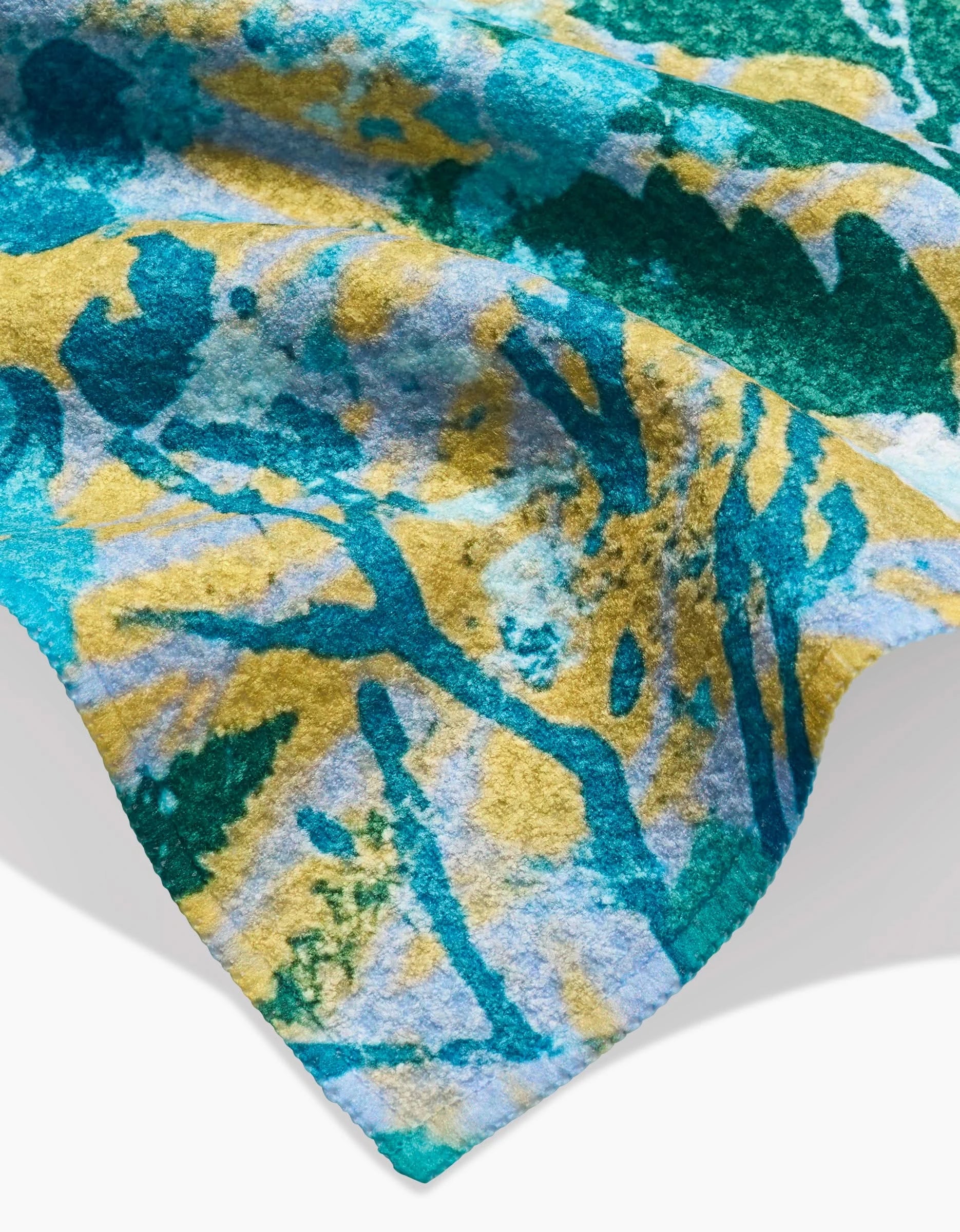 A close-up of the Leafy Bush Bar Towel by Taryn Brennan, crafted from Geoweave fabric with an abstract watercolor pattern in turquoise, teal, yellow, and white. Soft edges and subtle creases create a gentle shadow on the fabric.