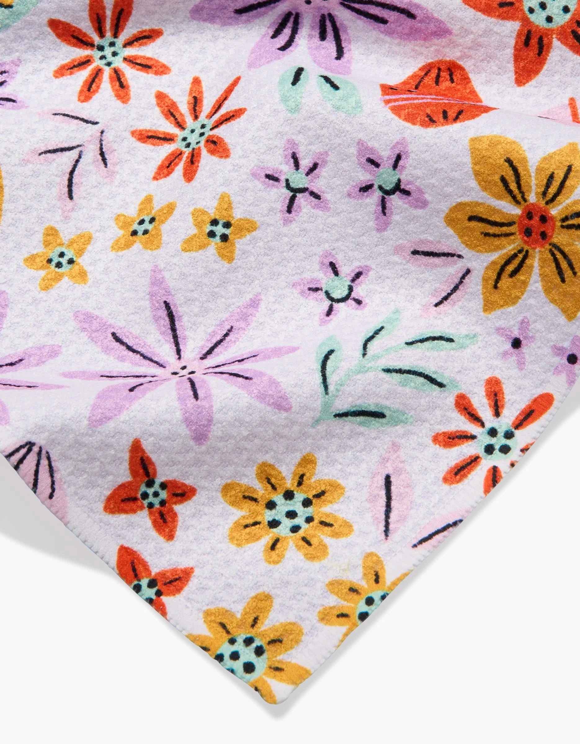 A close-up of Lilith, a white recycled kitchen towel from Amy MacCready, featuring a vibrant floral pattern with orange, yellow, purple, and red flowers plus green and black accents.