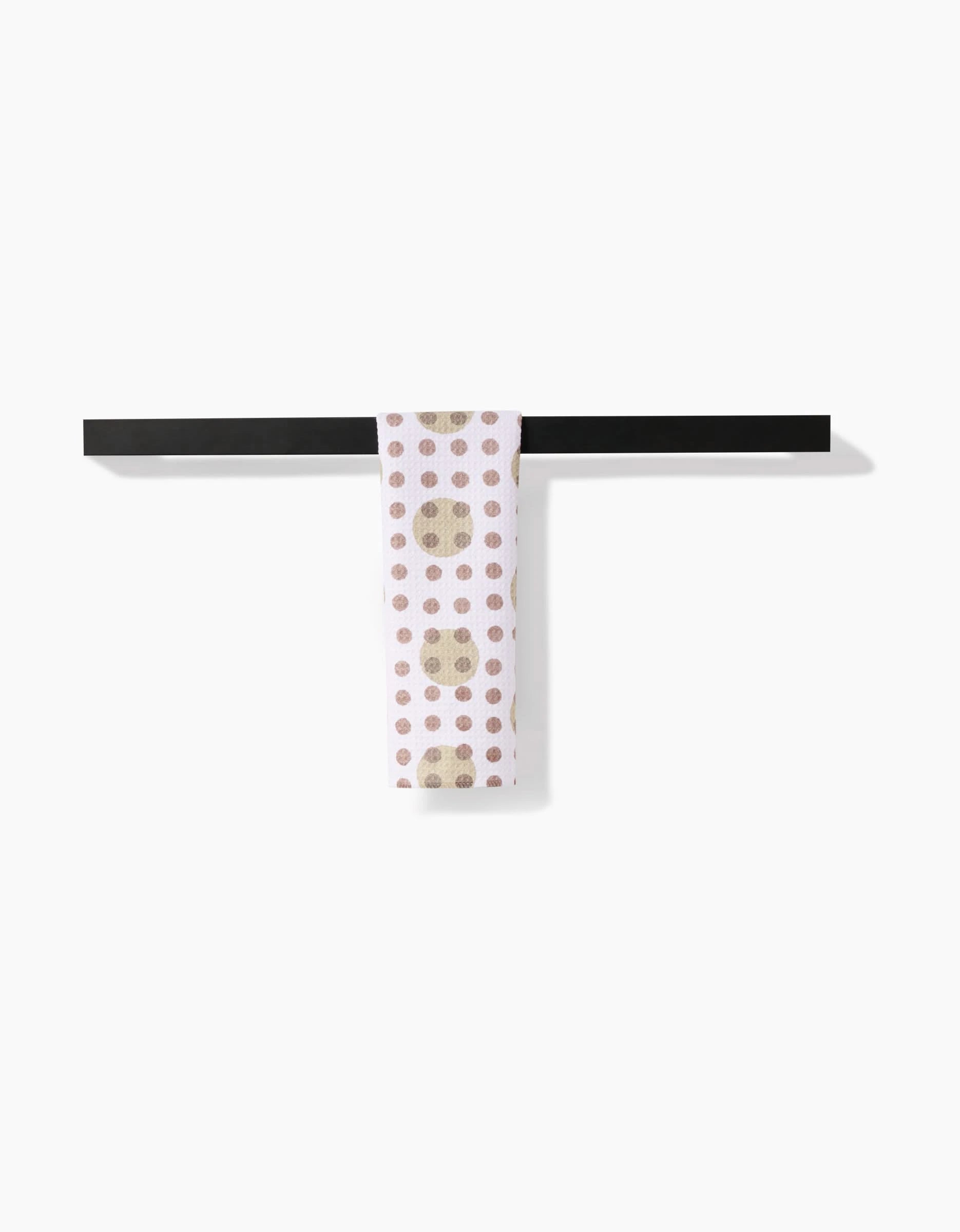The Studio Jeannot Lotty Dotty Bar Towel, featuring brown and beige polka dots on white ultra-absorbent Geoweave fabric, hangs over a black bar against a plain white background.