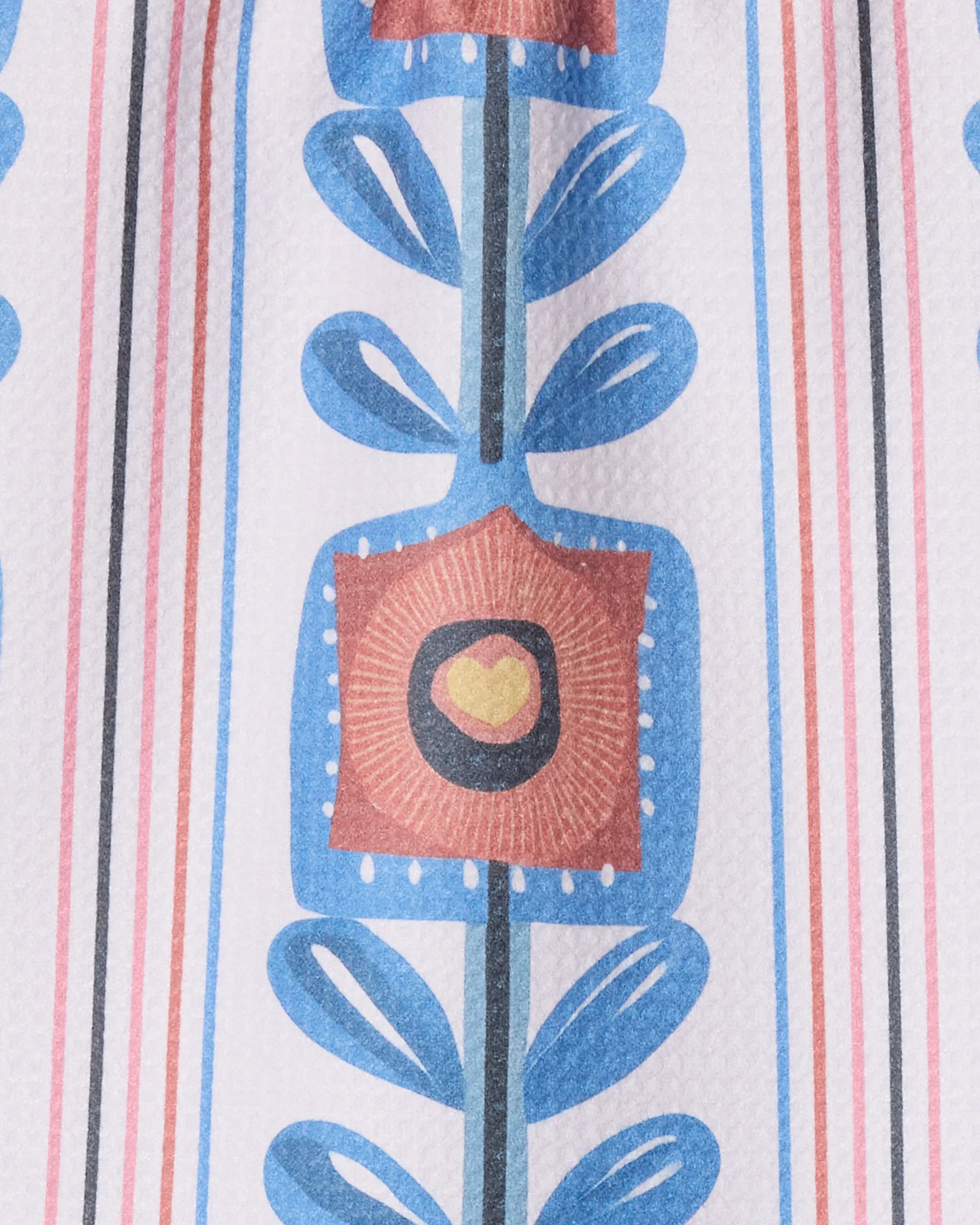 A close-up of Geometry's Lovestack towel, ultra-absorbent with a geometric floral pattern—blue leaves, a square orange flower with a yellow center, and vertical blue/red stripes on white.