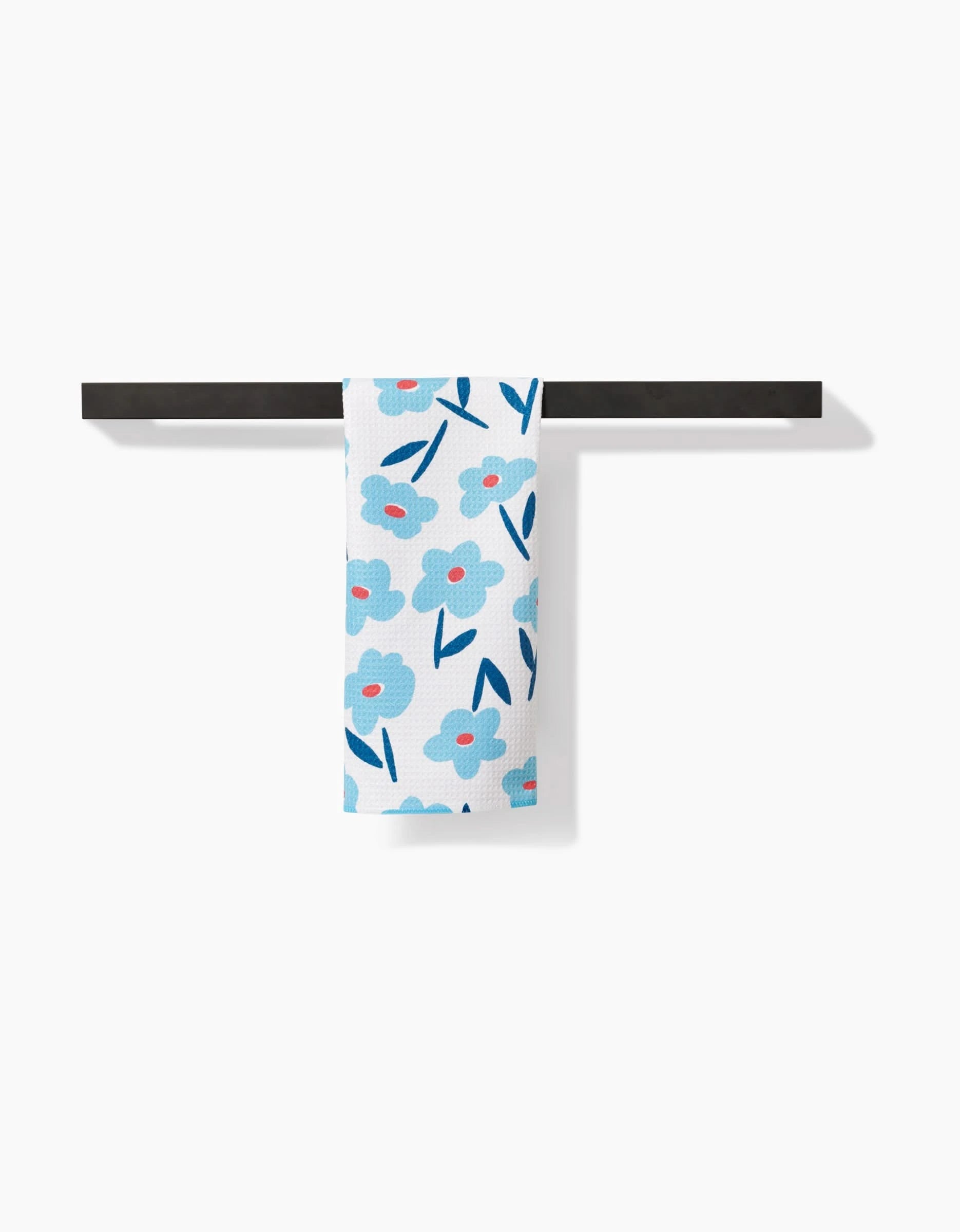 The Luca Daisy Bar Towel by Hufton Studio features blue flowers with pink centers and dark blue leaves on white Geoweave fabric, shown hanging neatly on a black towel bar against a white background.