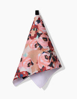 The Lucia towel by Ania Zwara Art features a textured, ultra-absorbent design with pink, red, and green floral patterns, hanging from a black loop against a white background.