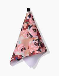 The Lucia towel by Ania Zwara Art features a textured, ultra-absorbent design with pink, red, and green floral patterns, hanging from a black loop against a white background.