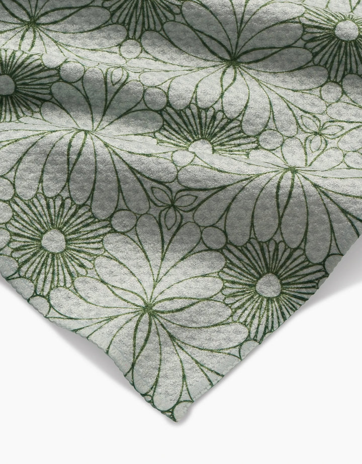 A close-up of Marta Harvey’s Lush Green Floral Bar Towel shows soft, ultra-absorbent light gray Geoweave fabric, featuring large, dark green outlined flowers and folded at the corner for a stylish touch.