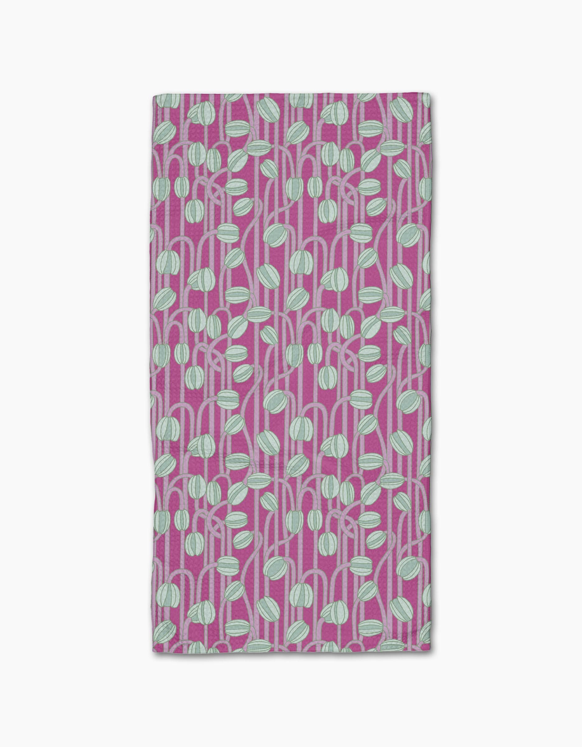The Magenta Poppy Pods bar towel by Katie OShea is ultra-absorbent and rectangular, featuring a modern, botanical pattern of light blue and white rounded leaf shapes with stems on a magenta background.