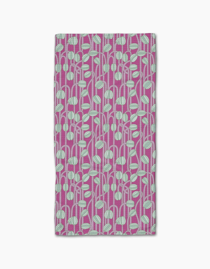 The Magenta Poppy Pods bar towel by Katie OShea is ultra-absorbent and rectangular, featuring a modern, botanical pattern of light blue and white rounded leaf shapes with stems on a magenta background.