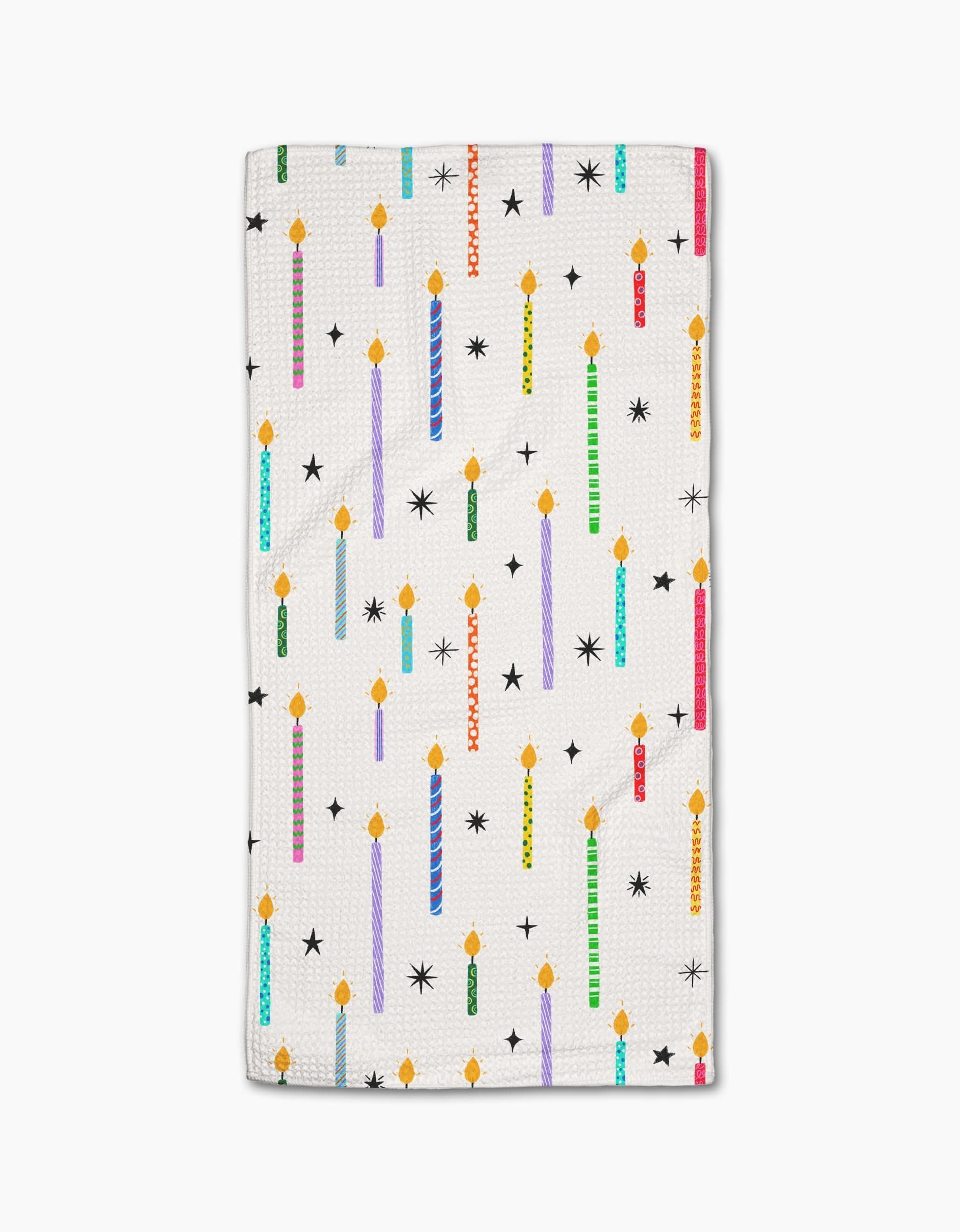 The Make A Wish bar towel by Vaishali Design Studio features colorful, lit birthday candles and black star shapes on white Geoweave fabric.