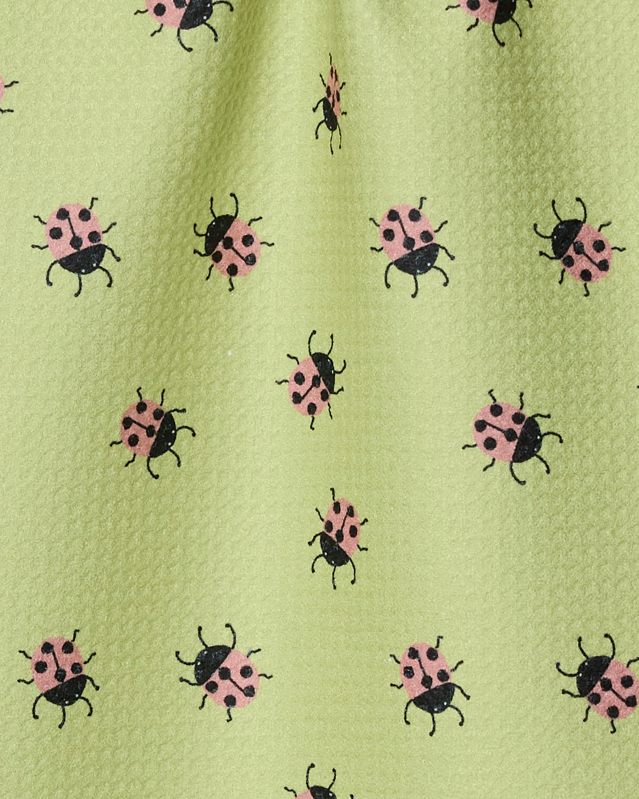 The Mariquita bar towel by Geometry features light green Geoweave fabric patterned with small pink and black ladybugs, all made from recycled materials for a playful touch.