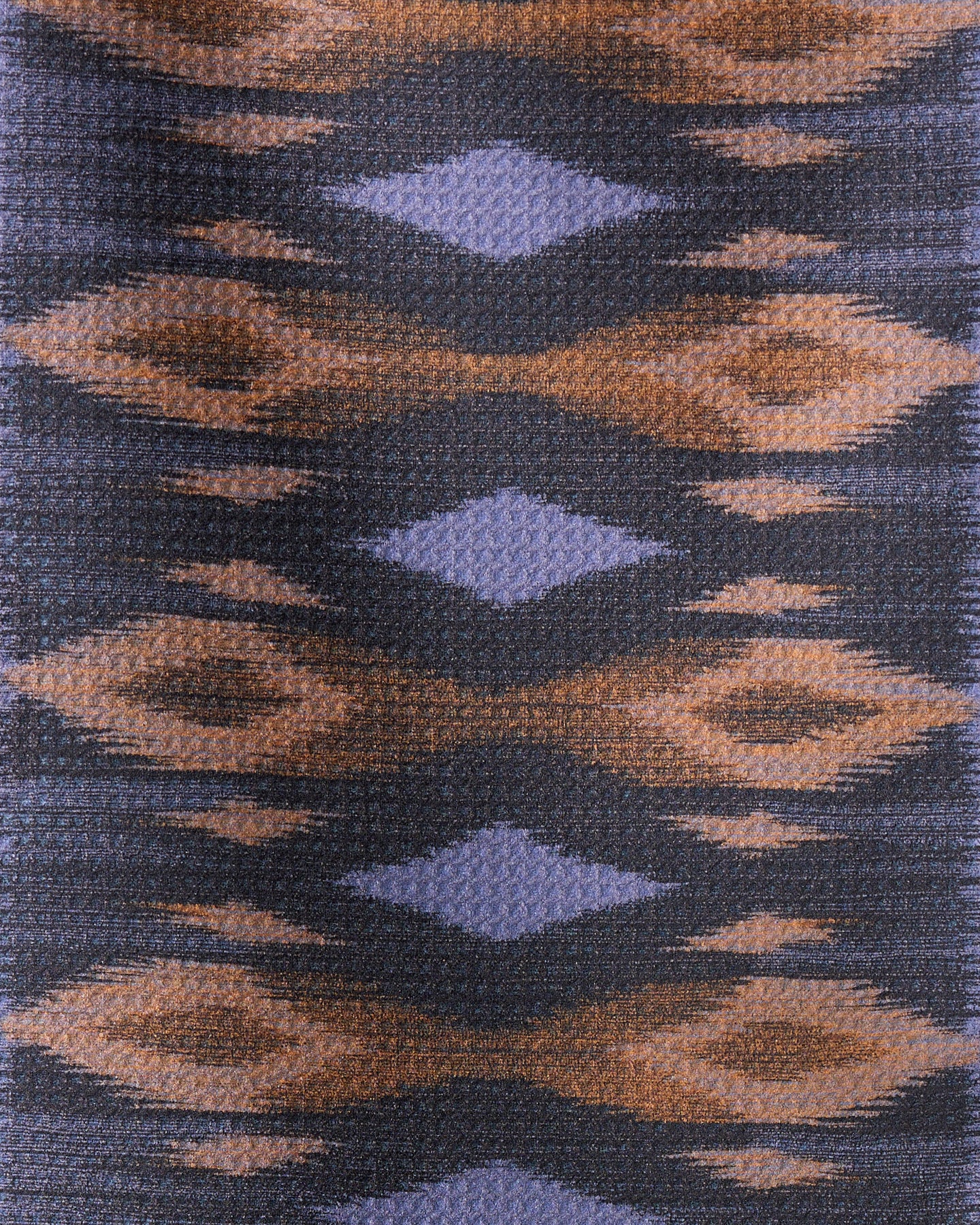 The Mesa recycled kitchen towel by Geometry features a woven, ultra-absorbent fabric with blue diamond shapes and brown, abstract eye-like designs arranged symmetrically on a dark background.