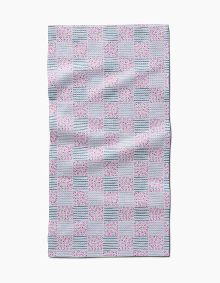 The Hufton Studio Mini Flowers and Stripes Check Pink and Green Bar Towel has a rectangular shape with alternating pink floral, green check, and striped squares, crafted from slightly wrinkled Geoweave fabric.