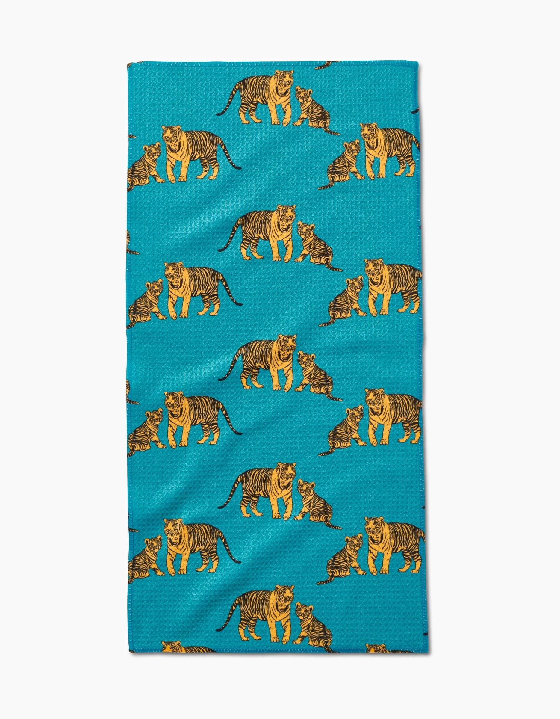 The Mommy and Me Bar Towel by Sarah Holden showcases orange and black illustrated tigers and cubs in playful poses on soft Geoweave fabric with a turquoise background.