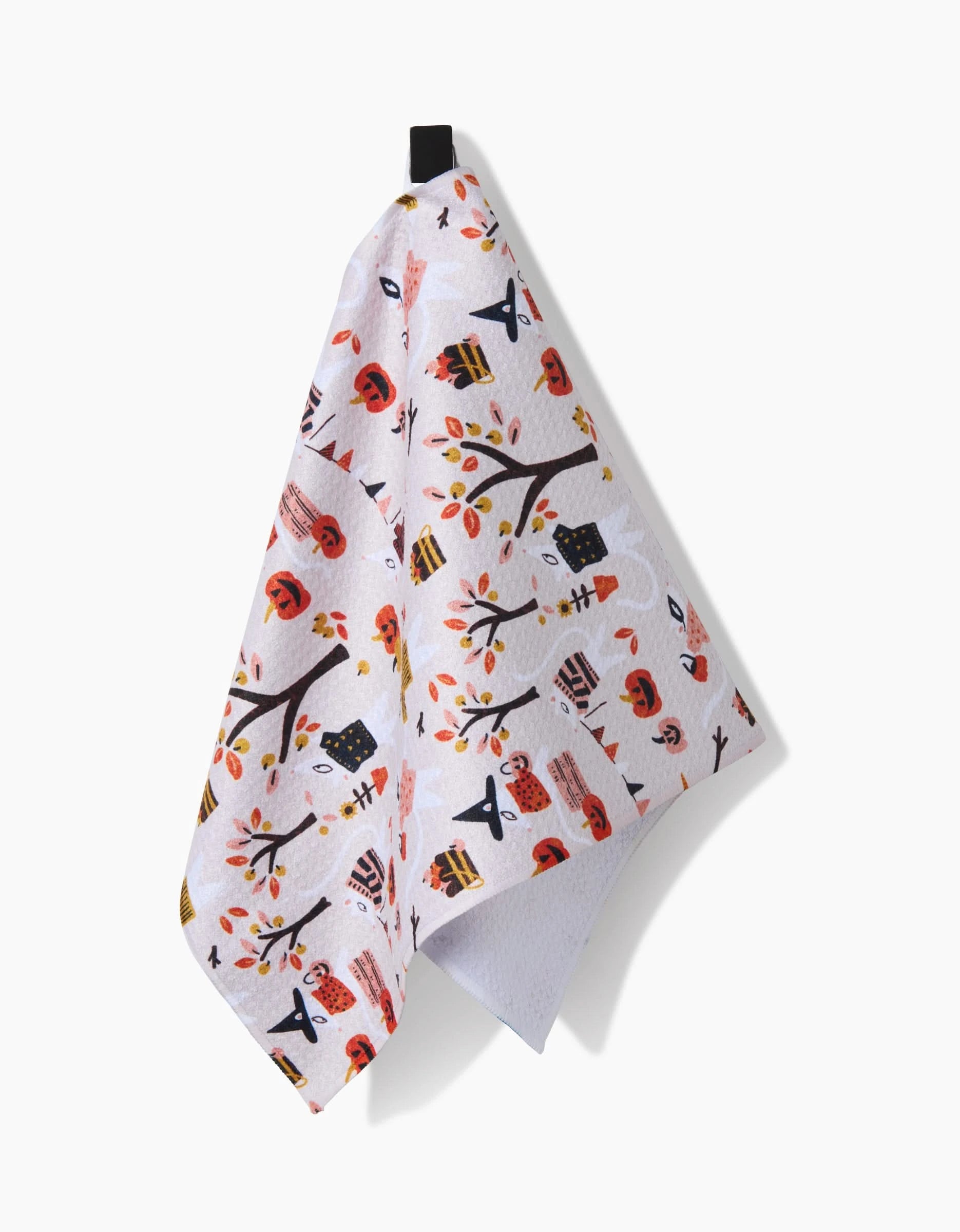 The Morticia towel by Amy MacCready is a white, ultra-absorbent kitchen bar towel with festive autumn illustrations—trees, pumpkins, mushrooms, acorns, and leaves—and hangs from a black loop for practical use.