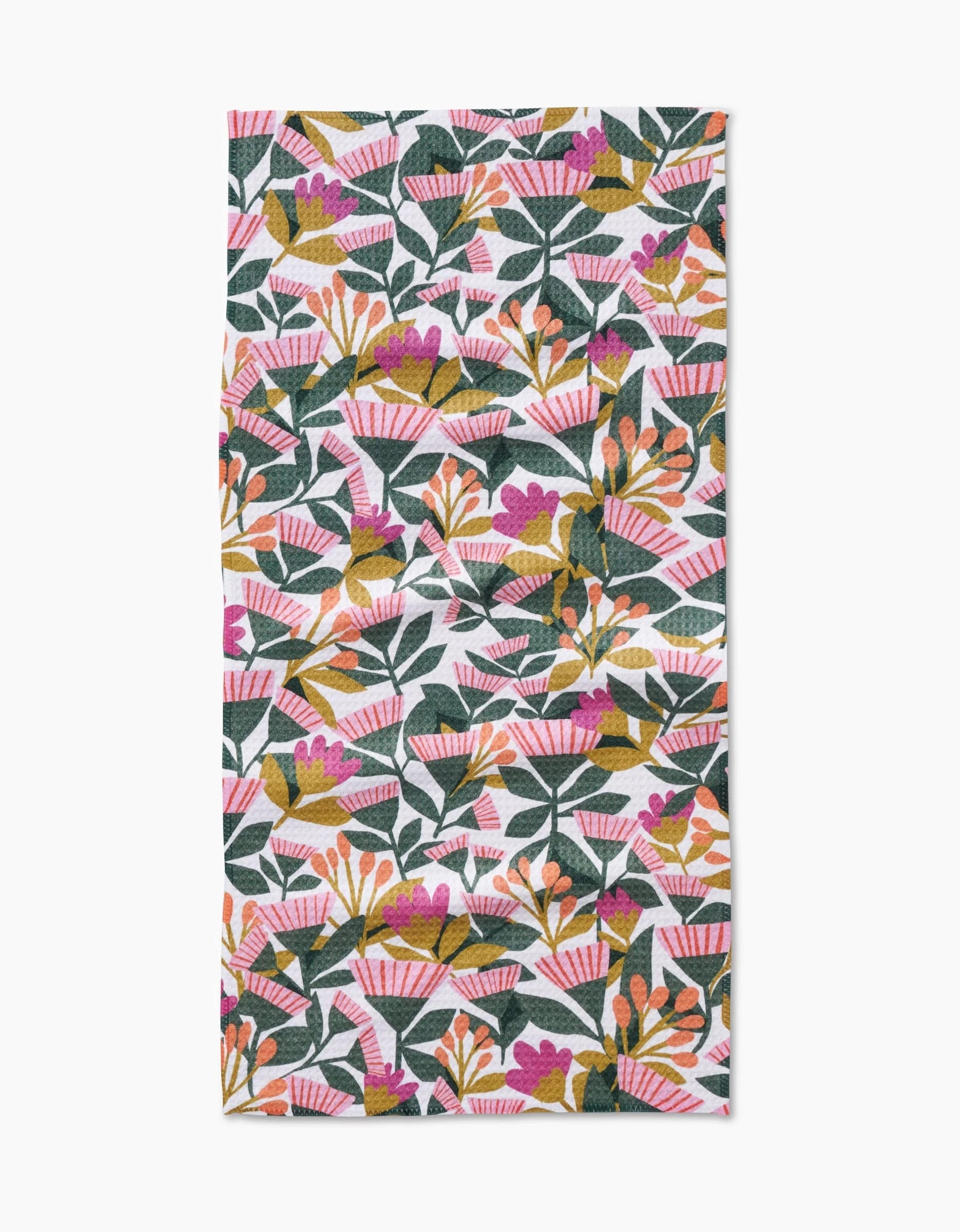 The Lisa Nelson Moxie Mauve bar towel showcases a vibrant botanical design of green leaves and colorful flowers on white Geoweave fabric, offering superior absorbency and durability.