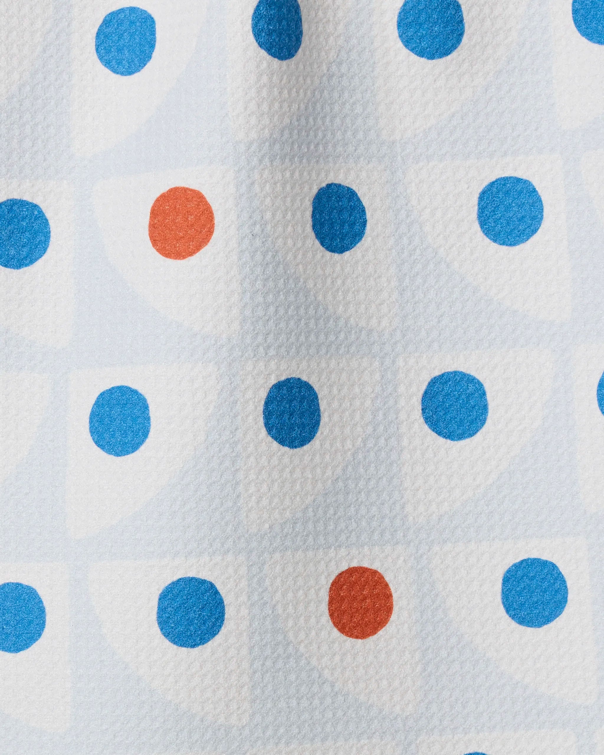 The Geometry Nautical Eye towel is ultra-absorbent and showcases repeating white quarter circles with blue and orange dots on a light blue background.