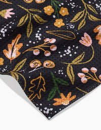 A close-up of Megan Roys Nighttime Botanical shows dark Geoweave fabric with yellow, pink, and orange floral patterns, green leaves, small white accents, and neatly stitched edges.