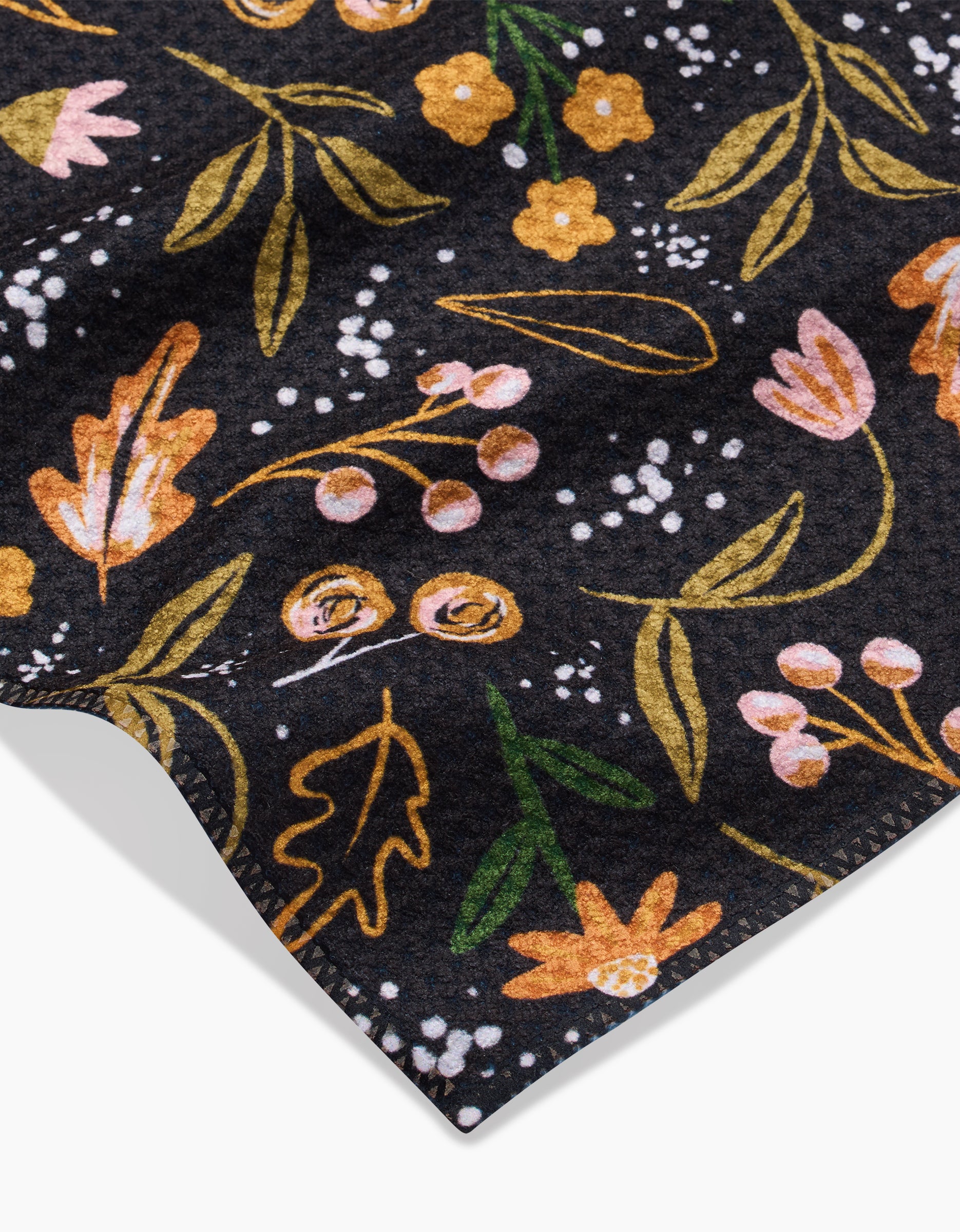 A close-up of Megan Roys Nighttime Botanical shows dark Geoweave fabric with yellow, pink, and orange floral patterns, green leaves, small white accents, and neatly stitched edges.