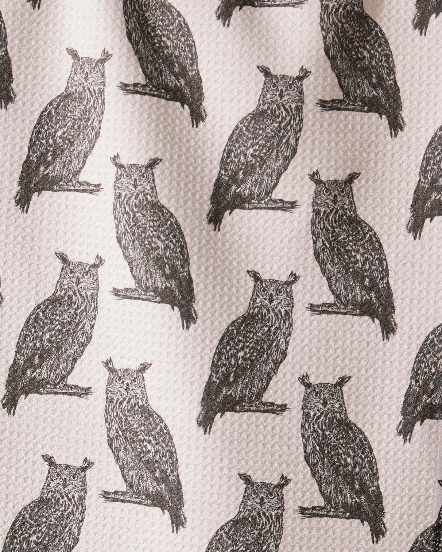 Nocturne by Geometry features detailed black owl illustrations facing forward, evenly spaced on an ultra-absorbent towel made from recycled materials with a textured, off-white background.
