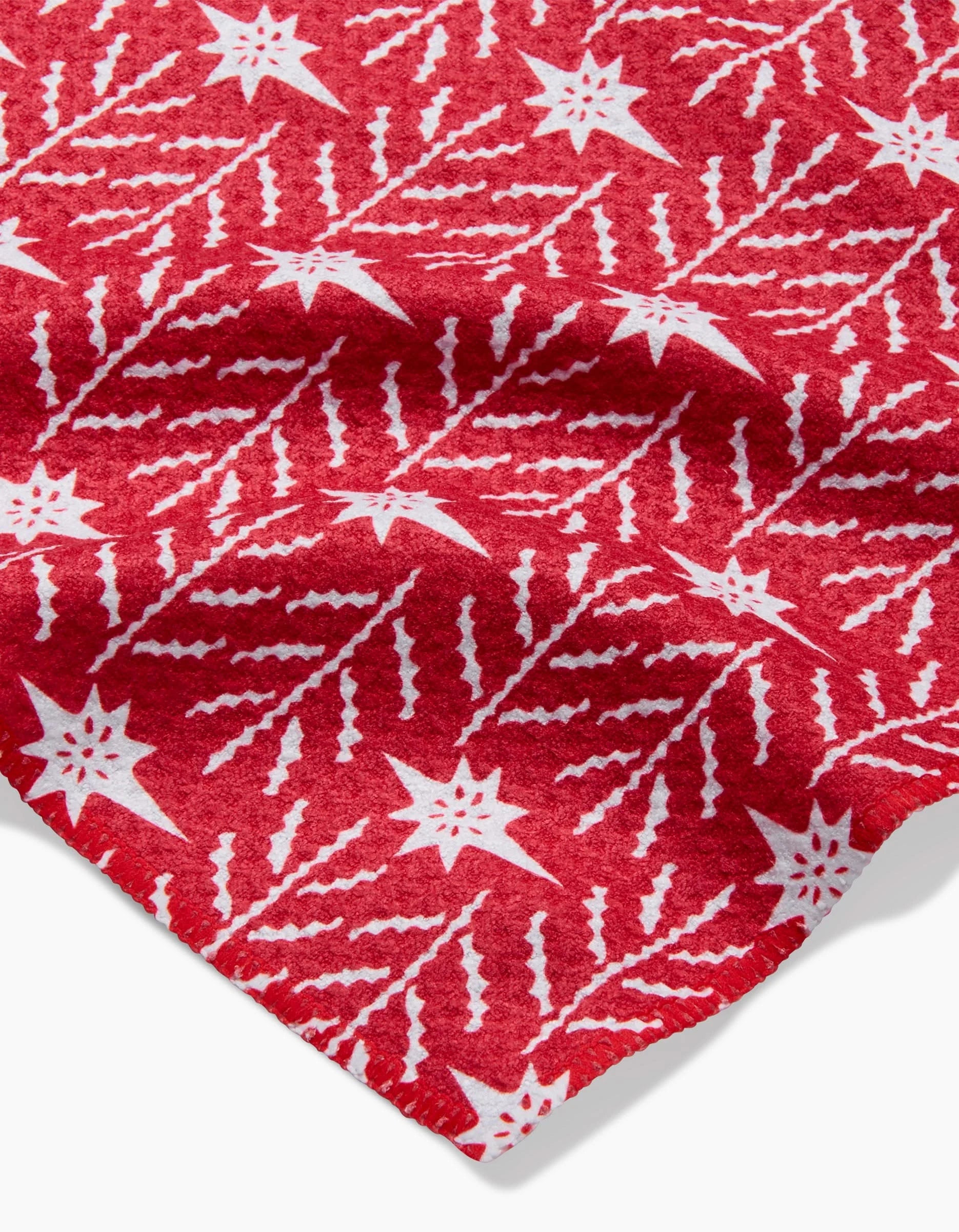 The North Star towel by Roxy Marj features ultra-absorbent red recycled fabric with a white repeating star and zigzag pattern—perfect for festive holiday décor or as a stylish bar towel. Slight corner fold shown for detail.