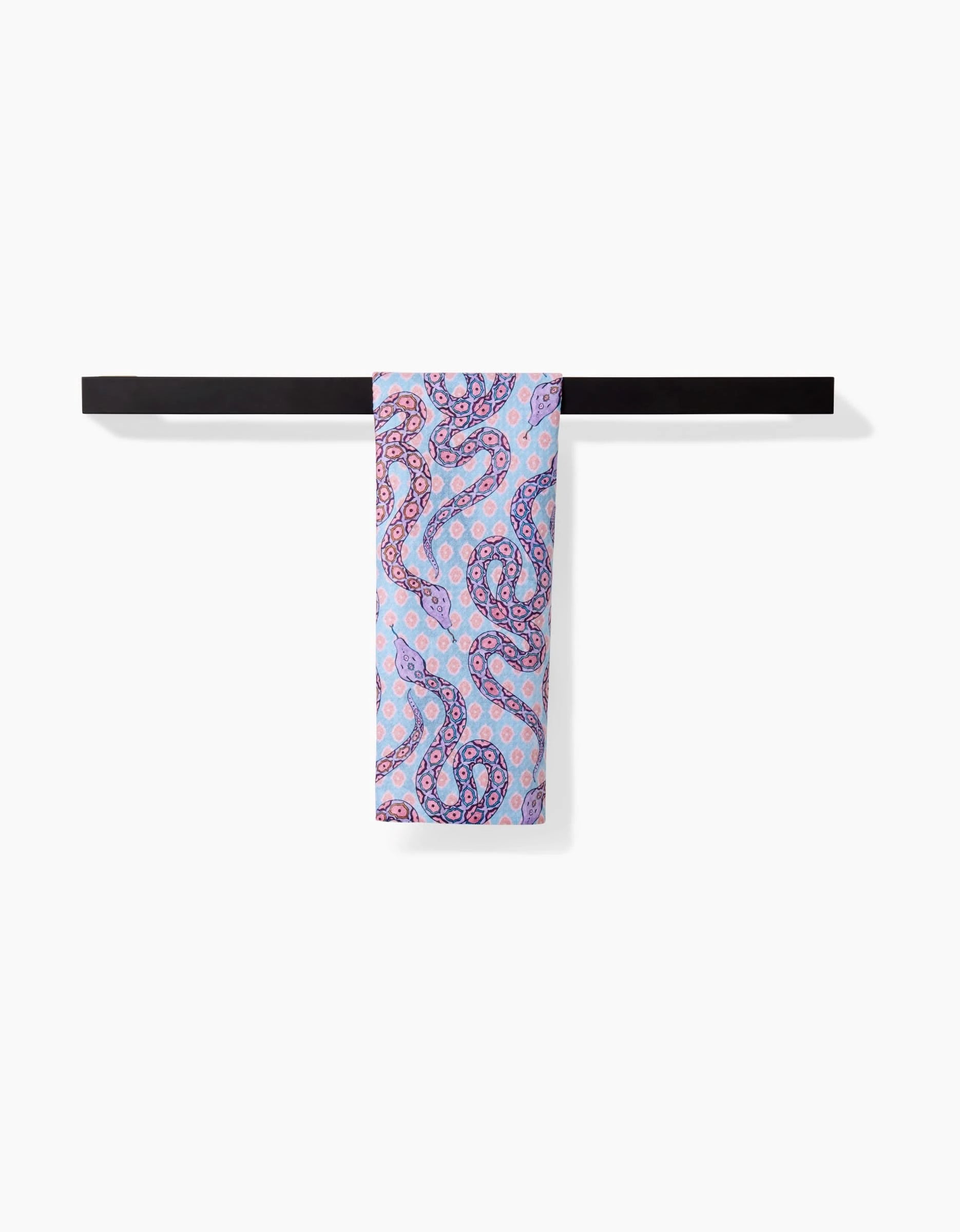 The Ophidia scarf by Maayan Alper-Swan, in light blue with a pink and purple paisley pattern, made of ultra-absorbent Geoweave fabric, is folded over a black rod against a plain white background.