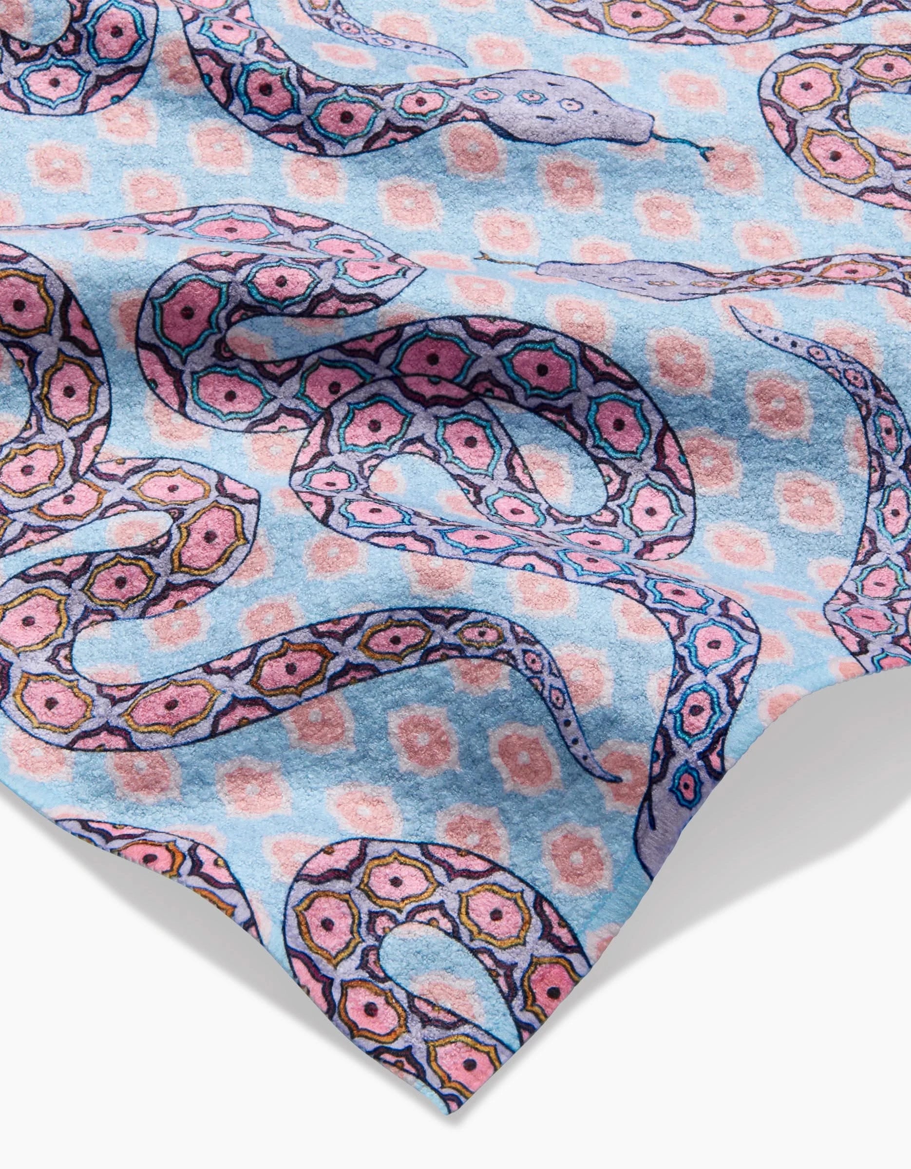 A close-up of the Ophidia bar towel by Maayan Alper-Swan shows its light blue Geoweave fabric with pink and purple octopus tentacles and geometric shapes. The ultra-absorbent material has a subtly wavy, textured look.