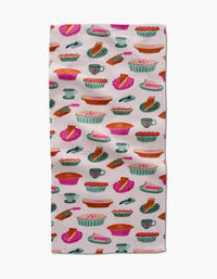 The Amy MacCready Orla Bar Towel showcases colorful illustrated pies, slices, and baking dishes in pink, orange, green, and blue on white Geoweave fabric for absorbency.