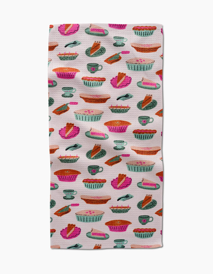 The Amy MacCready Orla Bar Towel showcases colorful illustrated pies, slices, and baking dishes in pink, orange, green, and blue on white Geoweave fabric for absorbency.