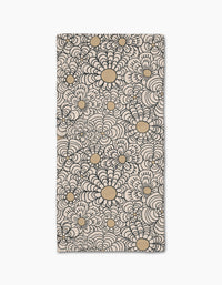 The Paulette bar towel by Amy MacCready showcases a bold black and tan floral pattern with large, stylized flower shapes on ultra-absorbent beige Geoweave fabric covering the entire rectangular surface.