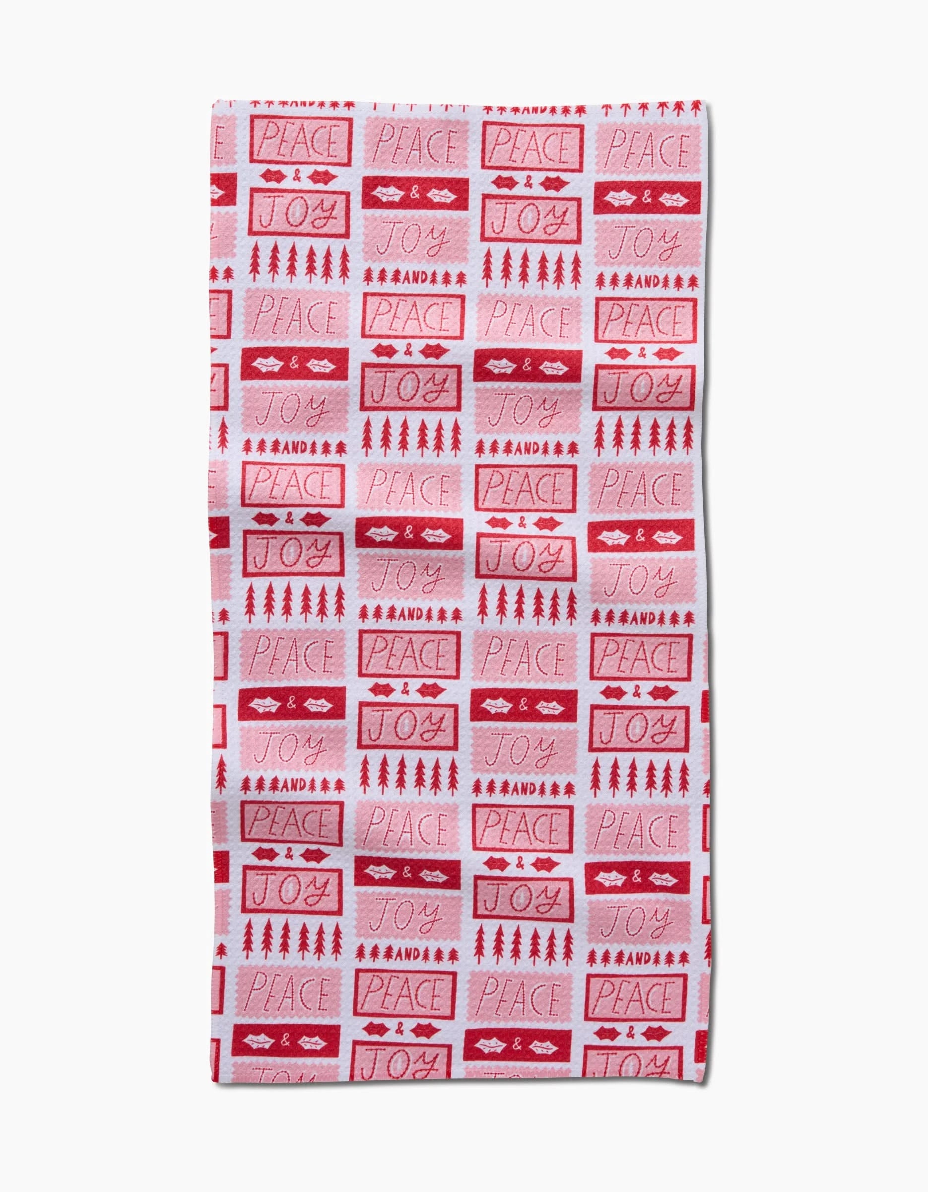 The Roxy Marj Peace Joy Stamps towel is a rectangular red and white ultra-absorbent piece with festive words and icons like PEACE, JOY, trees, hearts, and stars in varied fonts and arrangements.