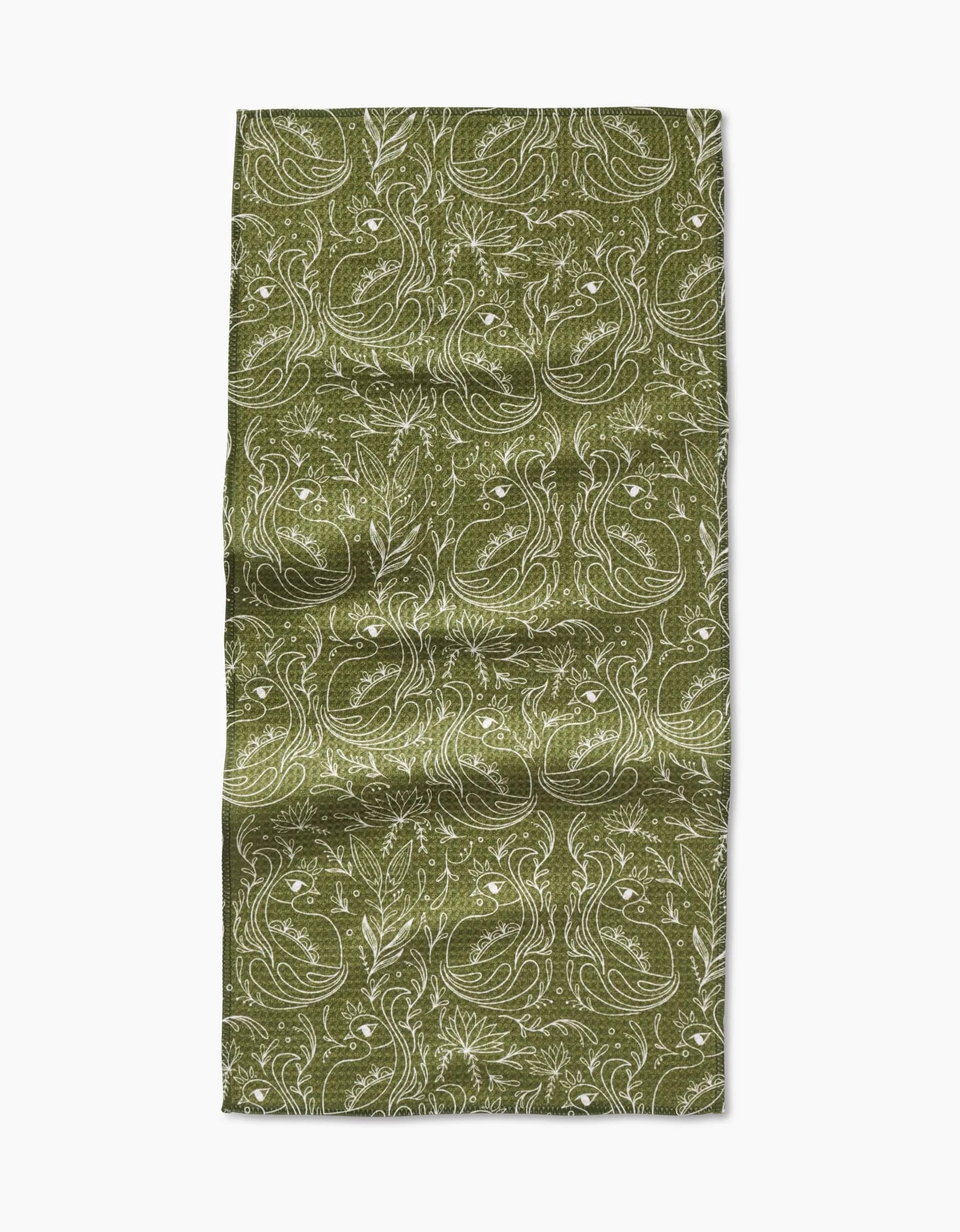 The Amita Nair Peacock Blooms Bar Towel is green and rectangular, made from Geoweave fabric, with a detailed white floral and leaf pattern. It appears slightly wrinkled and lies flat on a plain white background.
