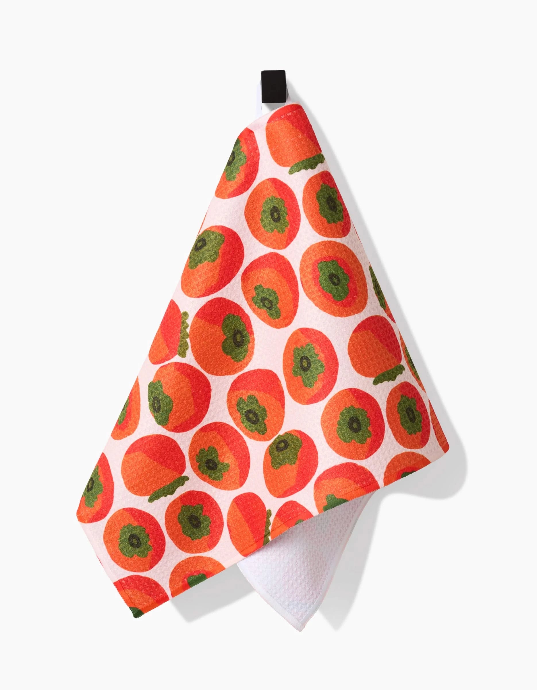 A white bar towel from Katie OShea called Persimmons, made from recycled materials, features a colorful persimmon pattern and hangs from a black loop.