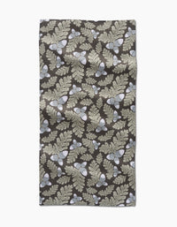The Danelys Sidron Pinecone Patch is a rectangular, ultra-absorbent towel featuring beige oak leaves and acorns on a dark brown background, shown flat with some wrinkles visible.
