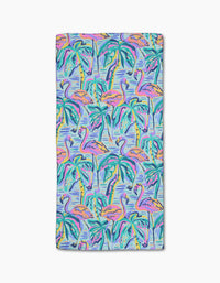 The Pink Flamingo beach towel by Masha Volnova is made from recycled materials and features a vibrant mix of pink flamingos, green palms, and pops of orange, purple, and turquoise on a light blue background.