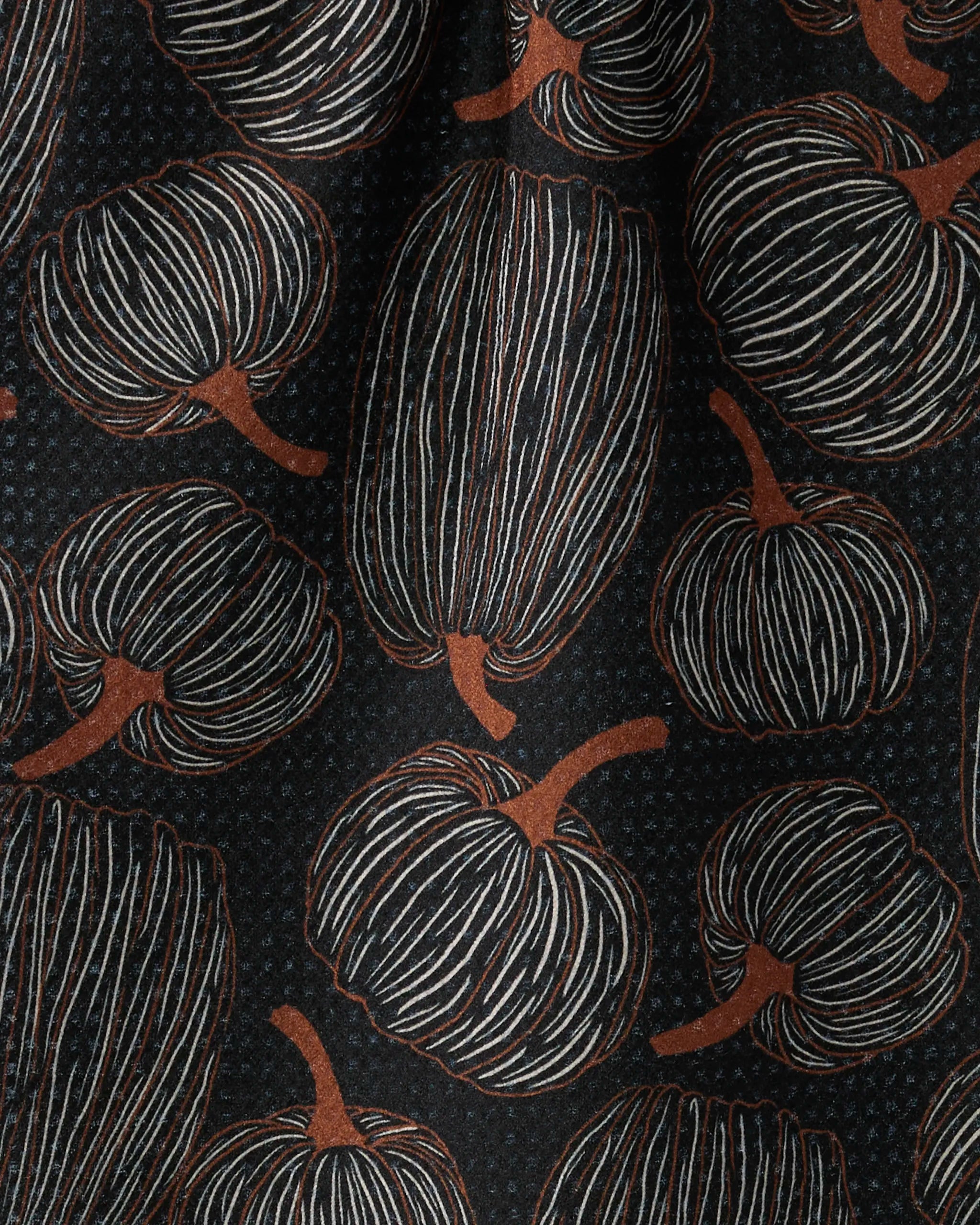 A close-up of Geometry’s ultra-absorbent Pinstripe Patch towel shows its patterned fabric—stylized pumpkins and gourds outlined in white and brown—set against a dark background.