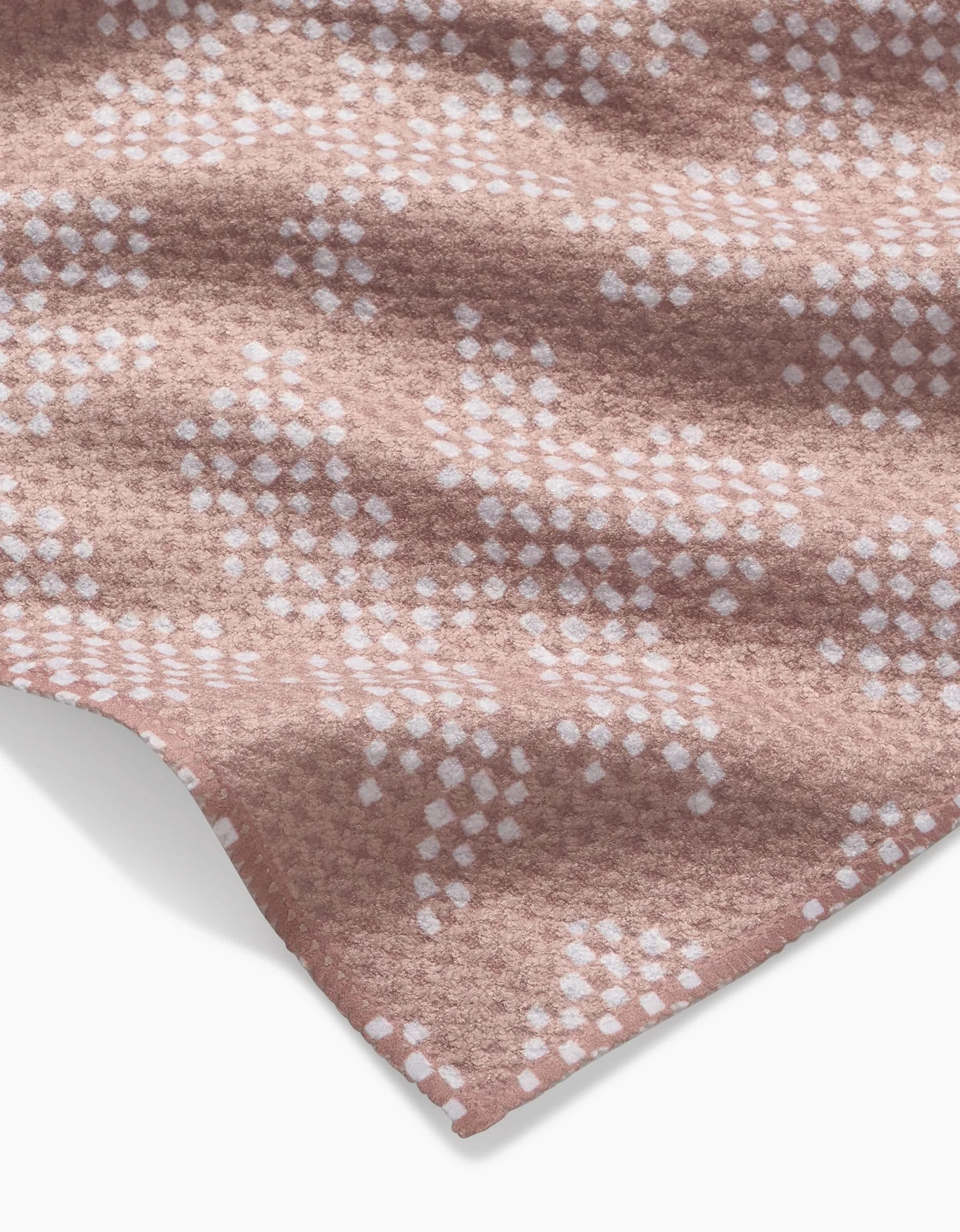 A close-up of Studio Jeannot’s Pixie Geoweave fabric: soft, cozy, and textured with a white geometric dot pattern on a pink background, crafted from recycled materials.