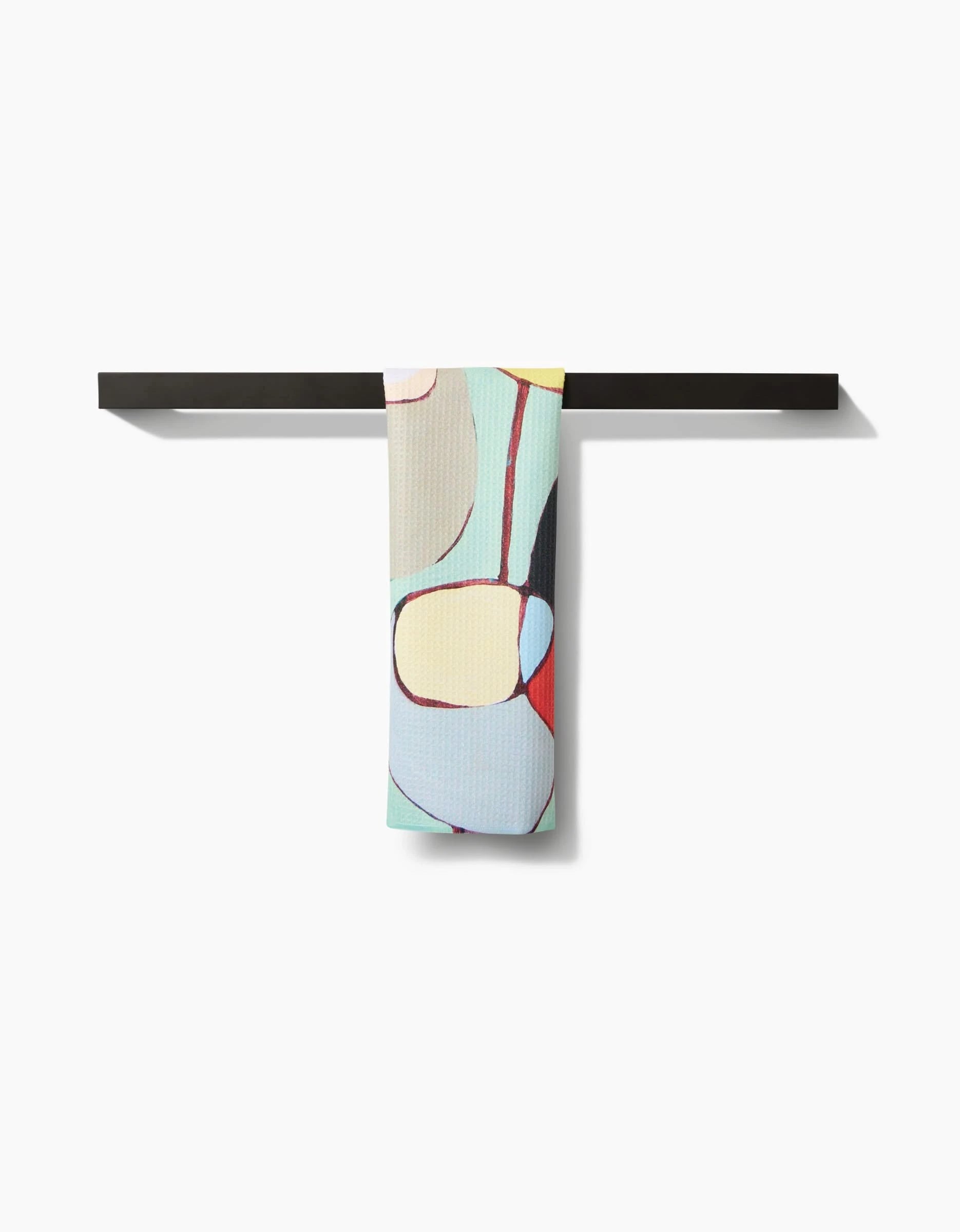 A modern black bar towel holder displays the Poppies on Mint towel by Rachel Austin, featuring a colorful abstract pattern on Geoweave fabric with curved pastel shapes against a white background.